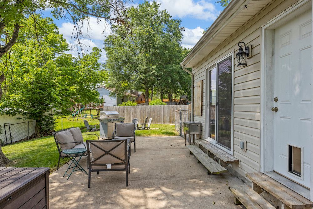 The backyard of a house with a patio and sliding glass doors.