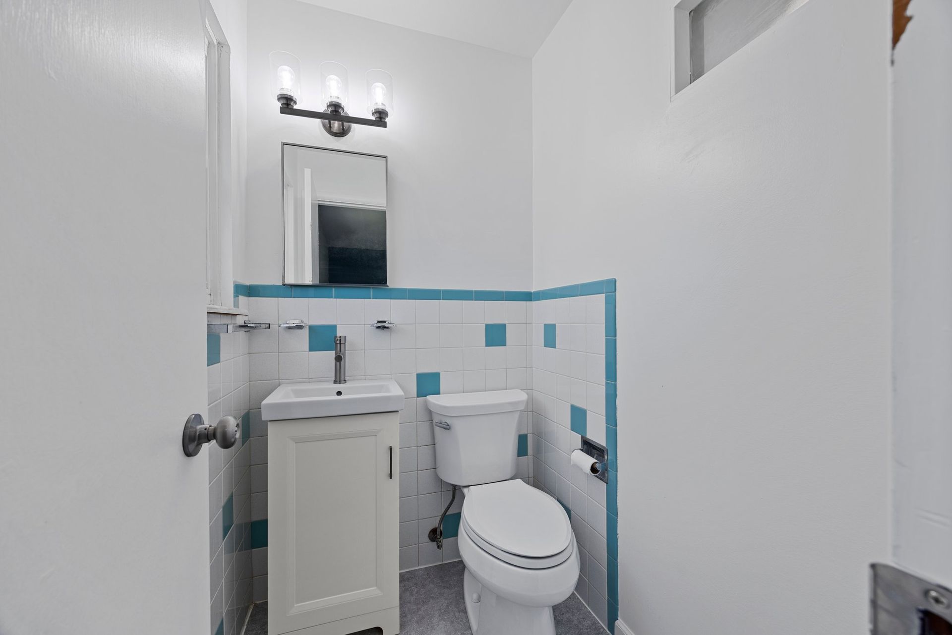 A bathroom with a toilet , sink and mirror.
