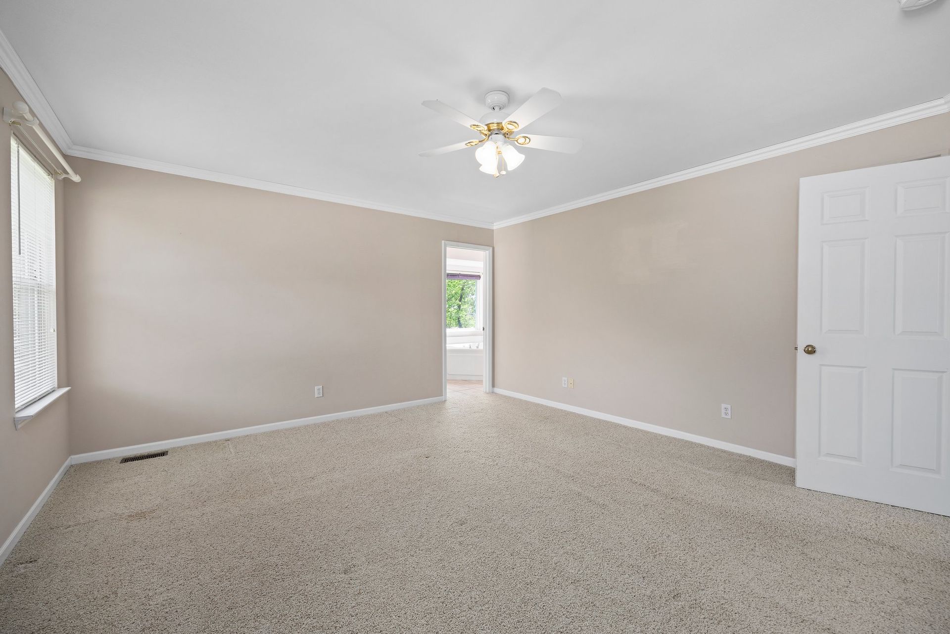 An empty bedroom with a ceiling fan and a window.