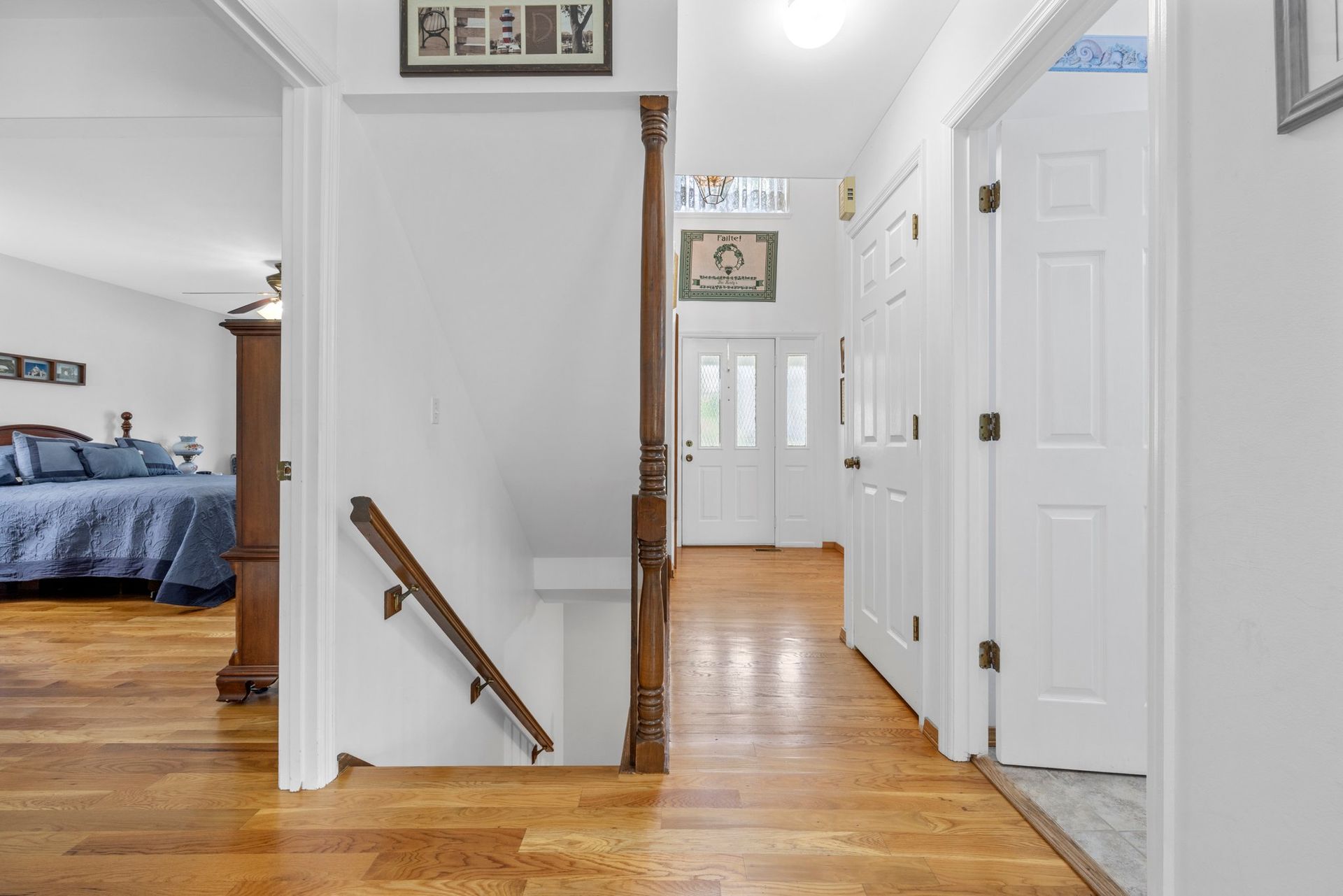A hallway with hardwood floors and stairs leading up to the second floor of a house.