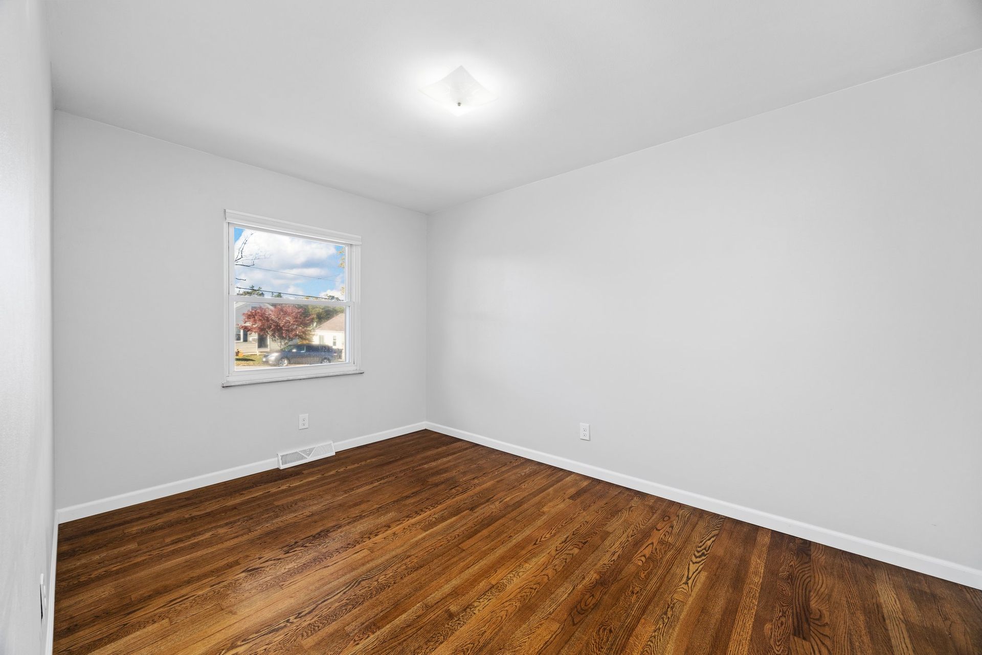 An empty room with hardwood floors and a window.