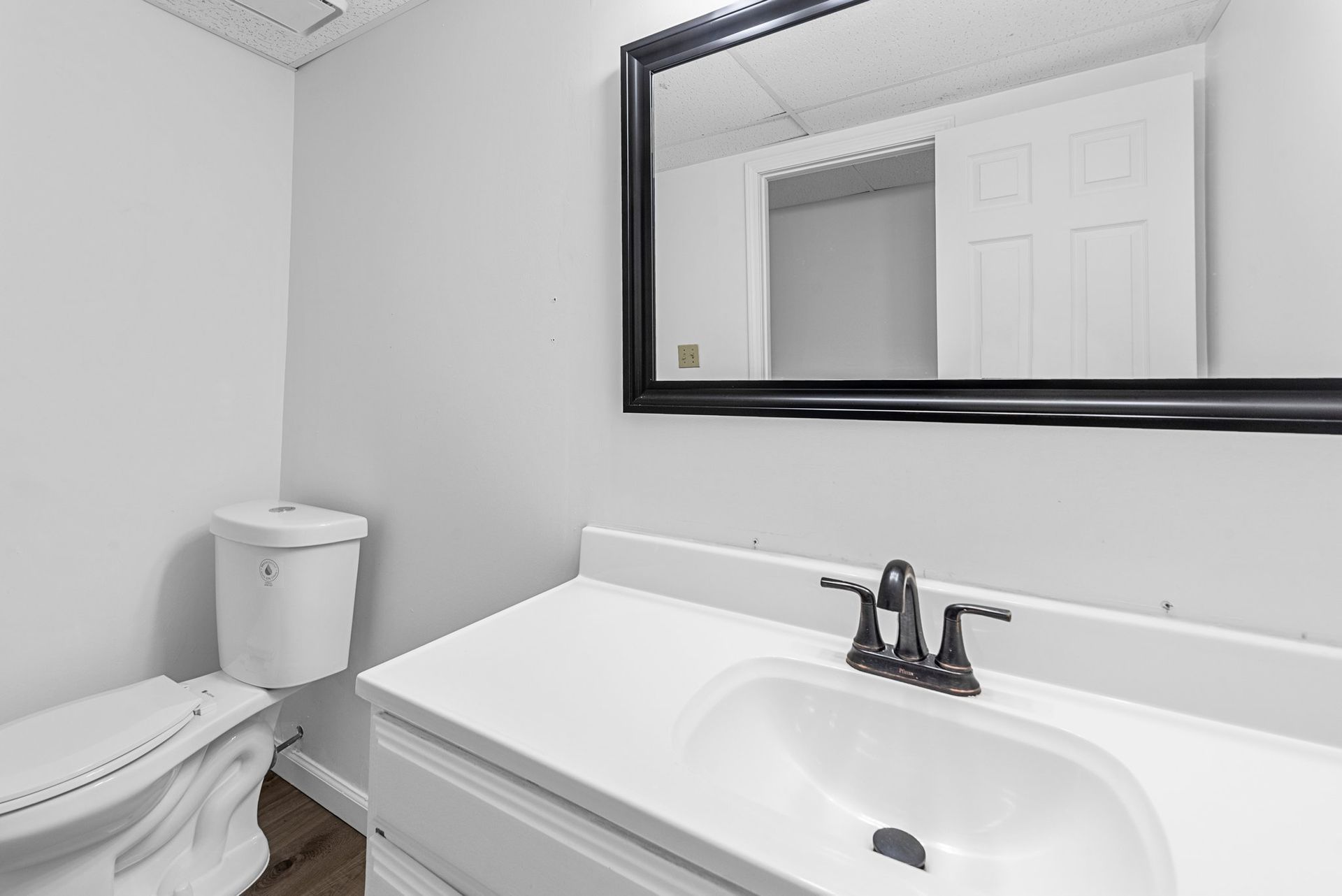 A bathroom with a toilet , sink and mirror.