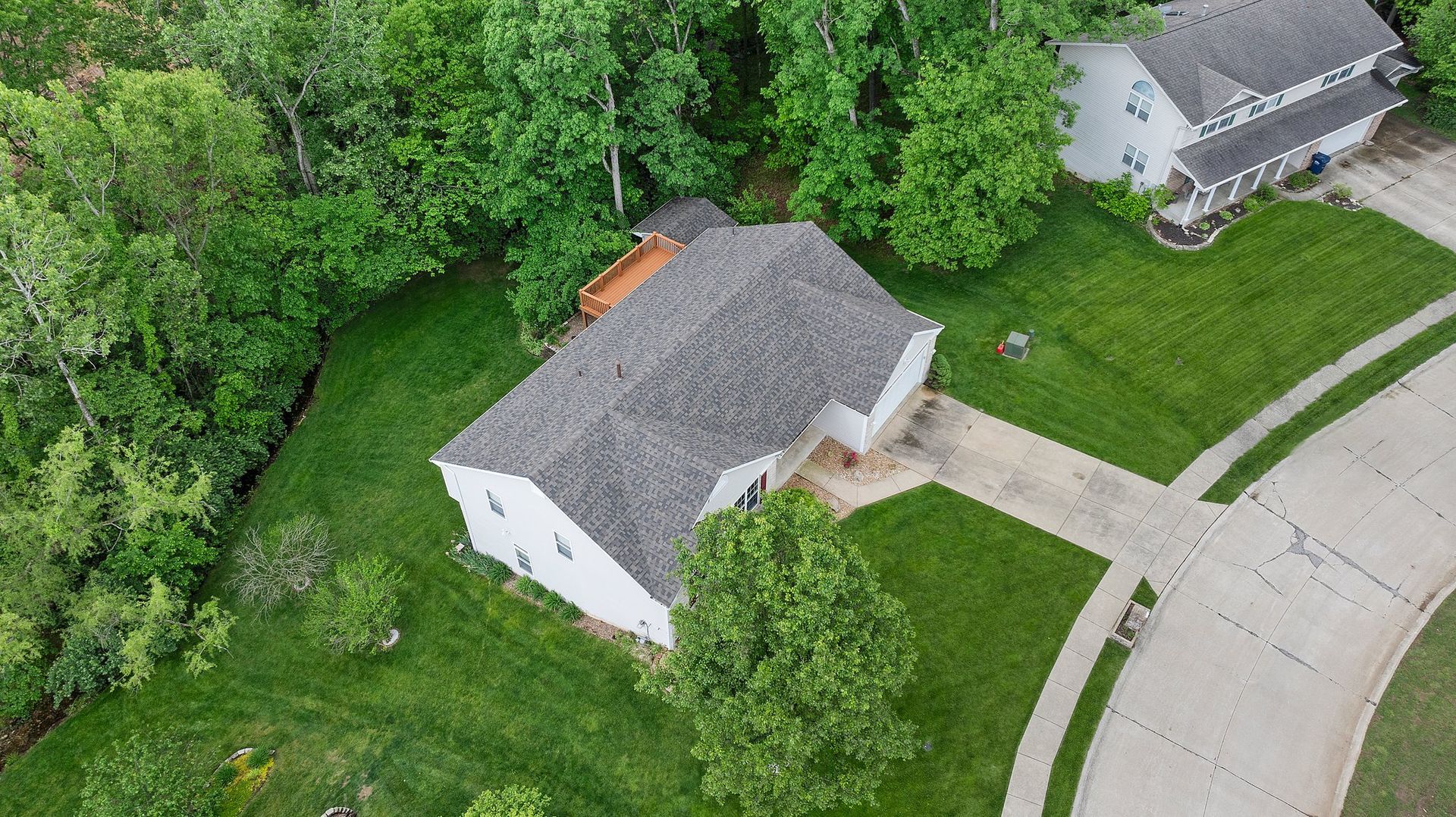 An aerial view of a house in a residential area surrounded by trees.