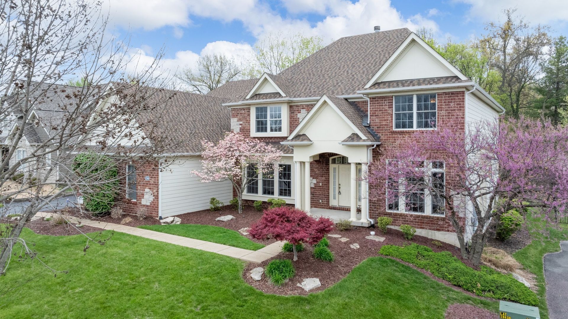 An aerial view of a large brick house with a lush green lawn.