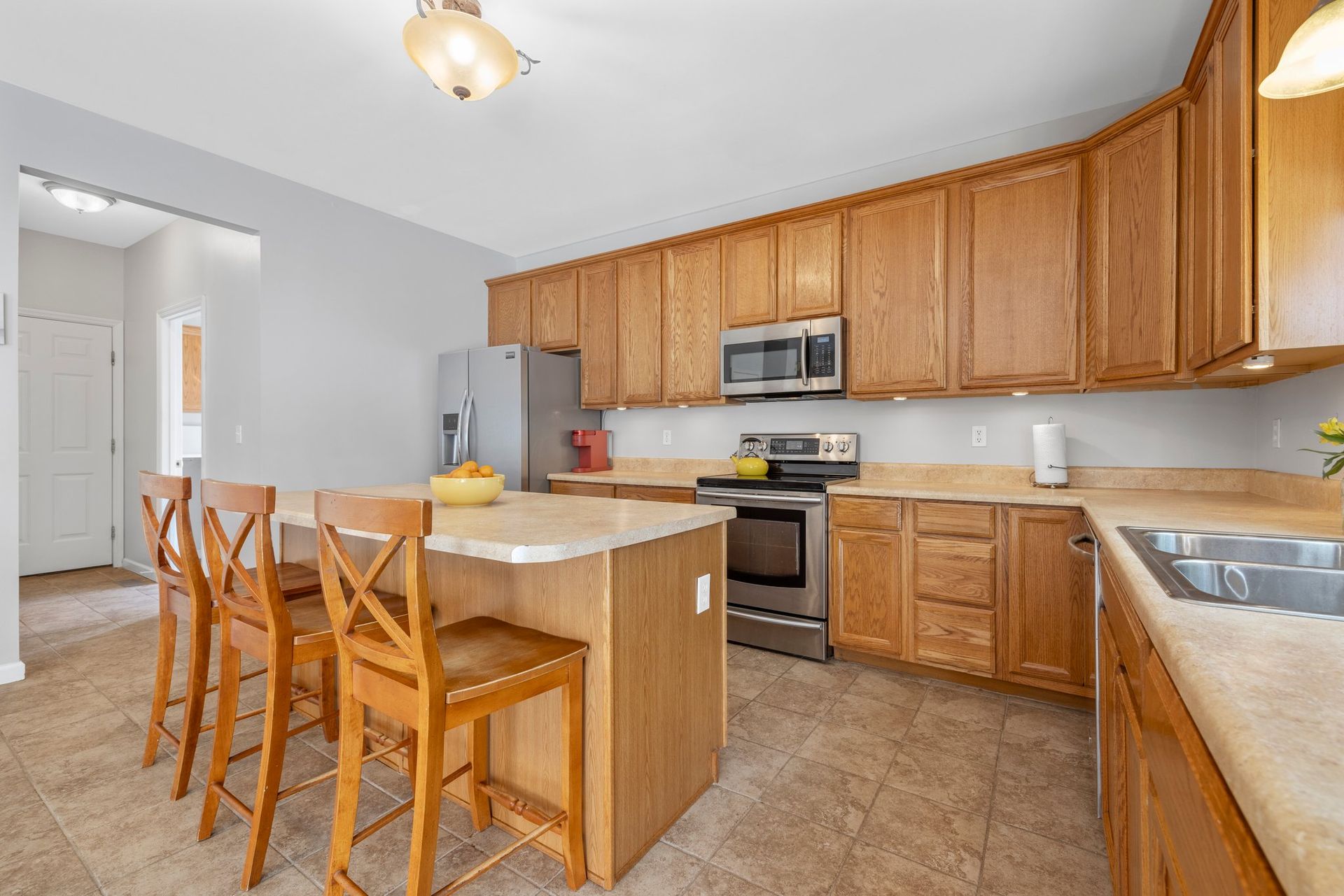 A kitchen with wooden cabinets , stainless steel appliances , and a large island.