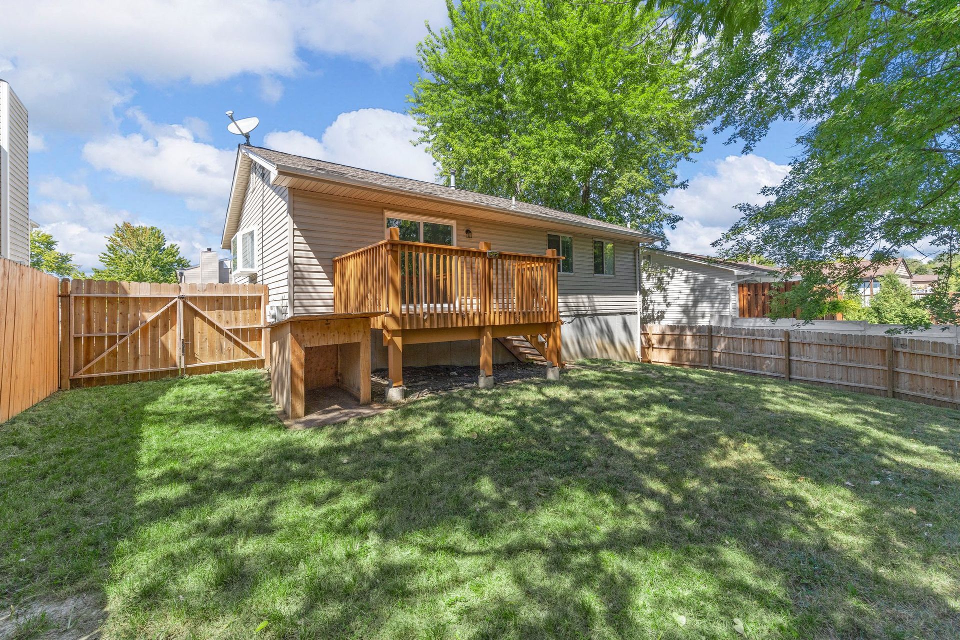The backyard of a house with a large deck and a wooden fence.