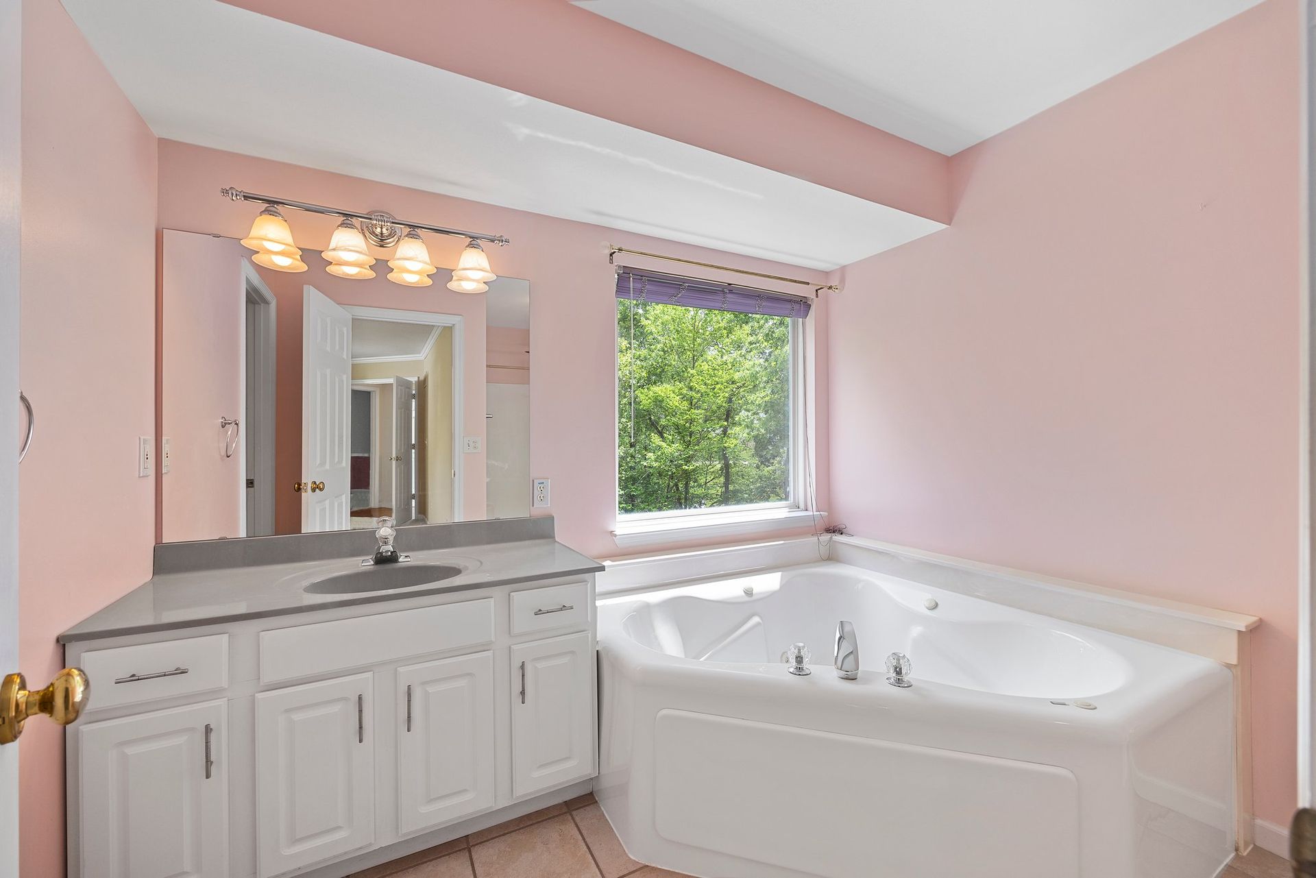 A bathroom with pink walls and a jacuzzi tub.