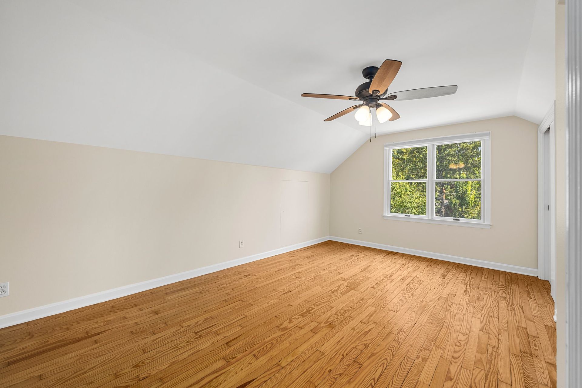 An empty room with hardwood floors and a ceiling fan.