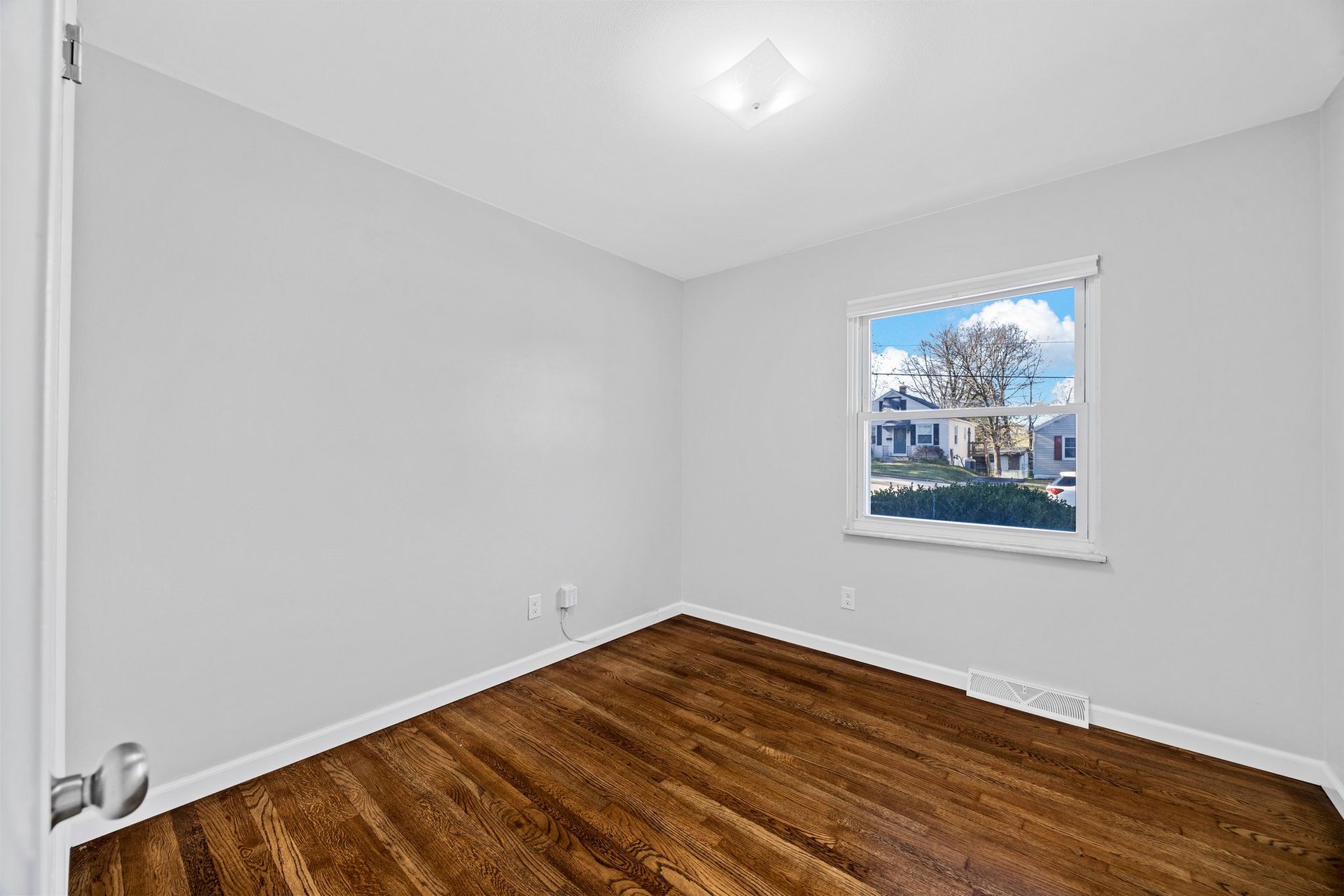 An empty room with hardwood floors and a window.