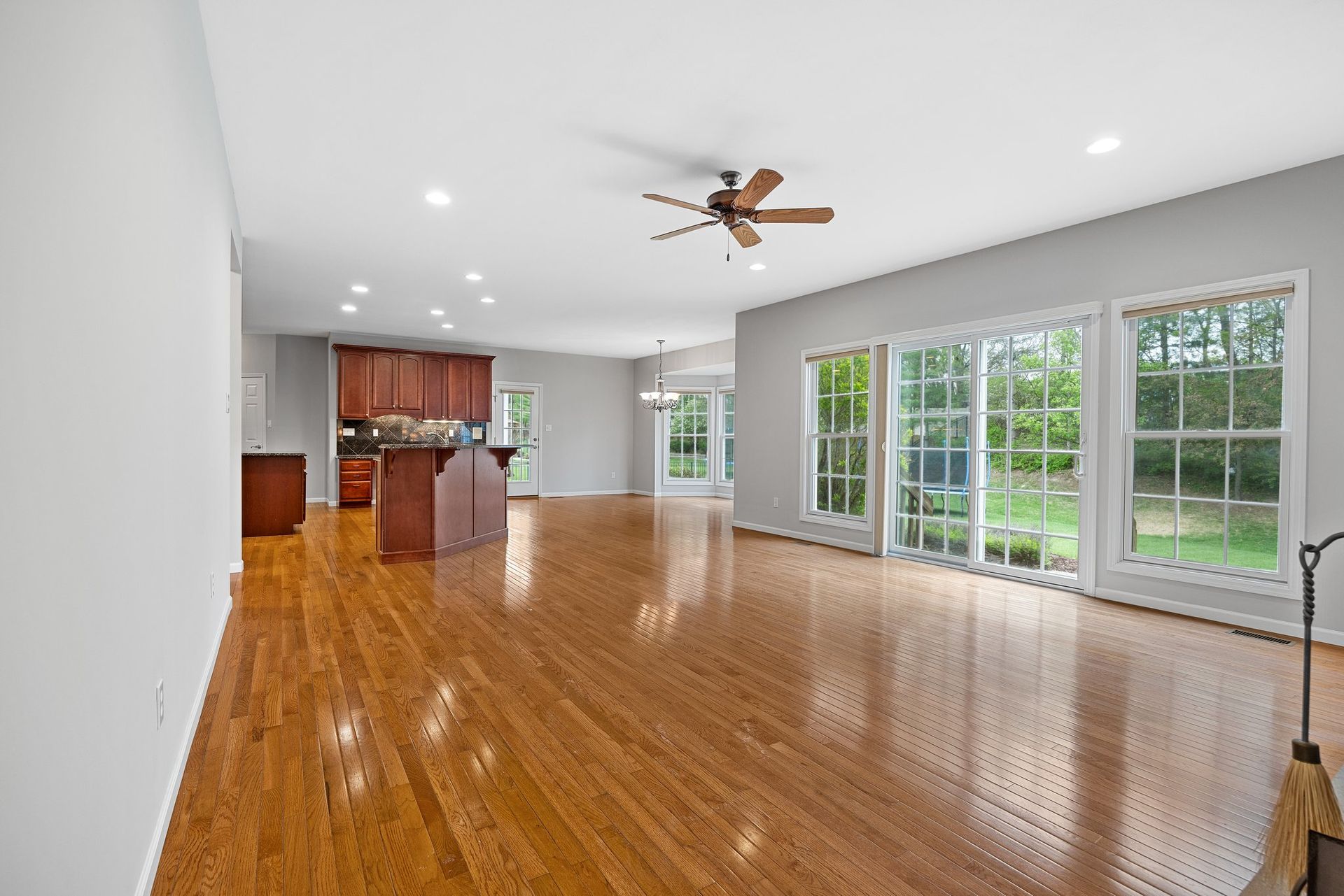 An empty living room with hardwood floors and a ceiling fan.