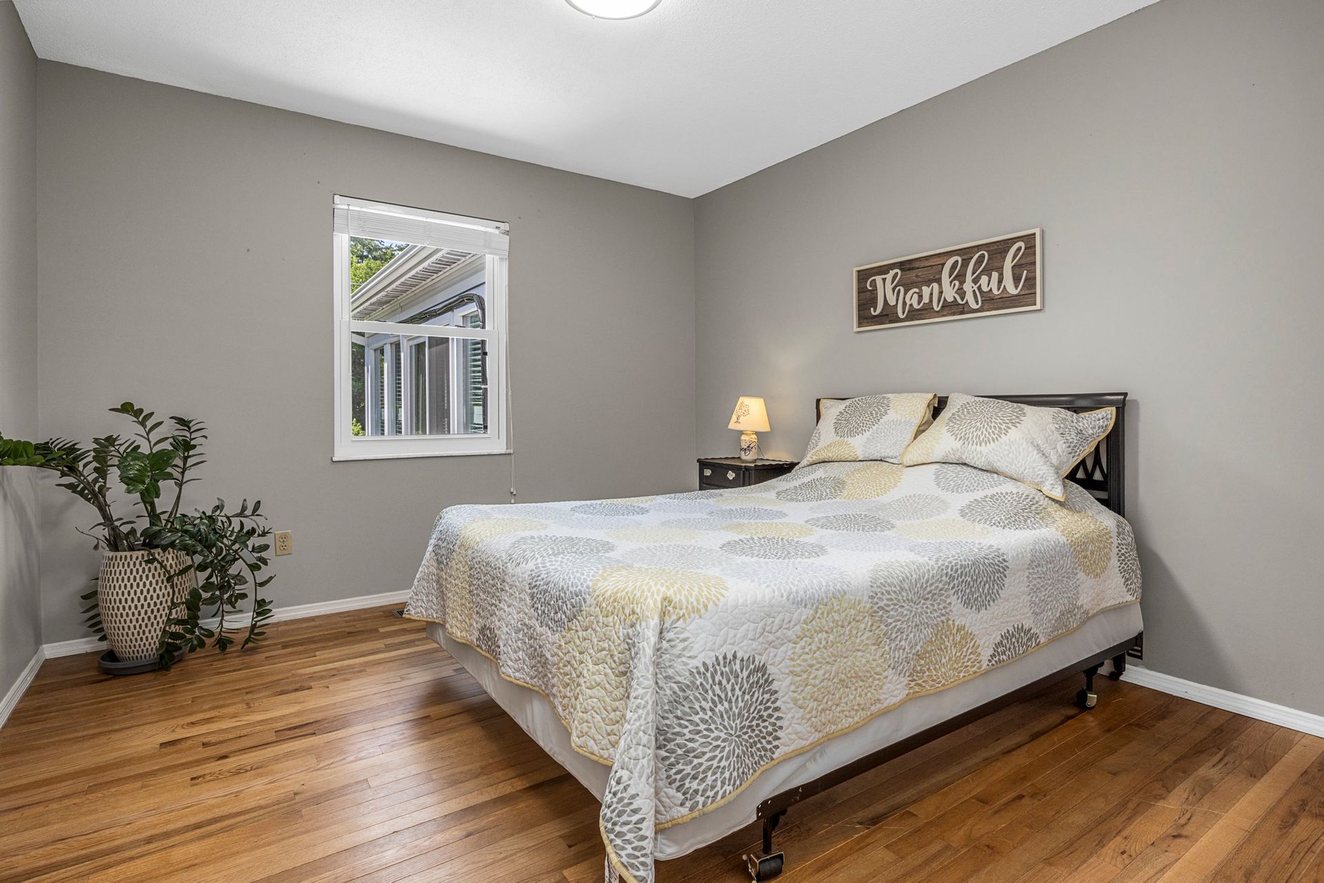 A bedroom with a bed , wooden floors and a window.