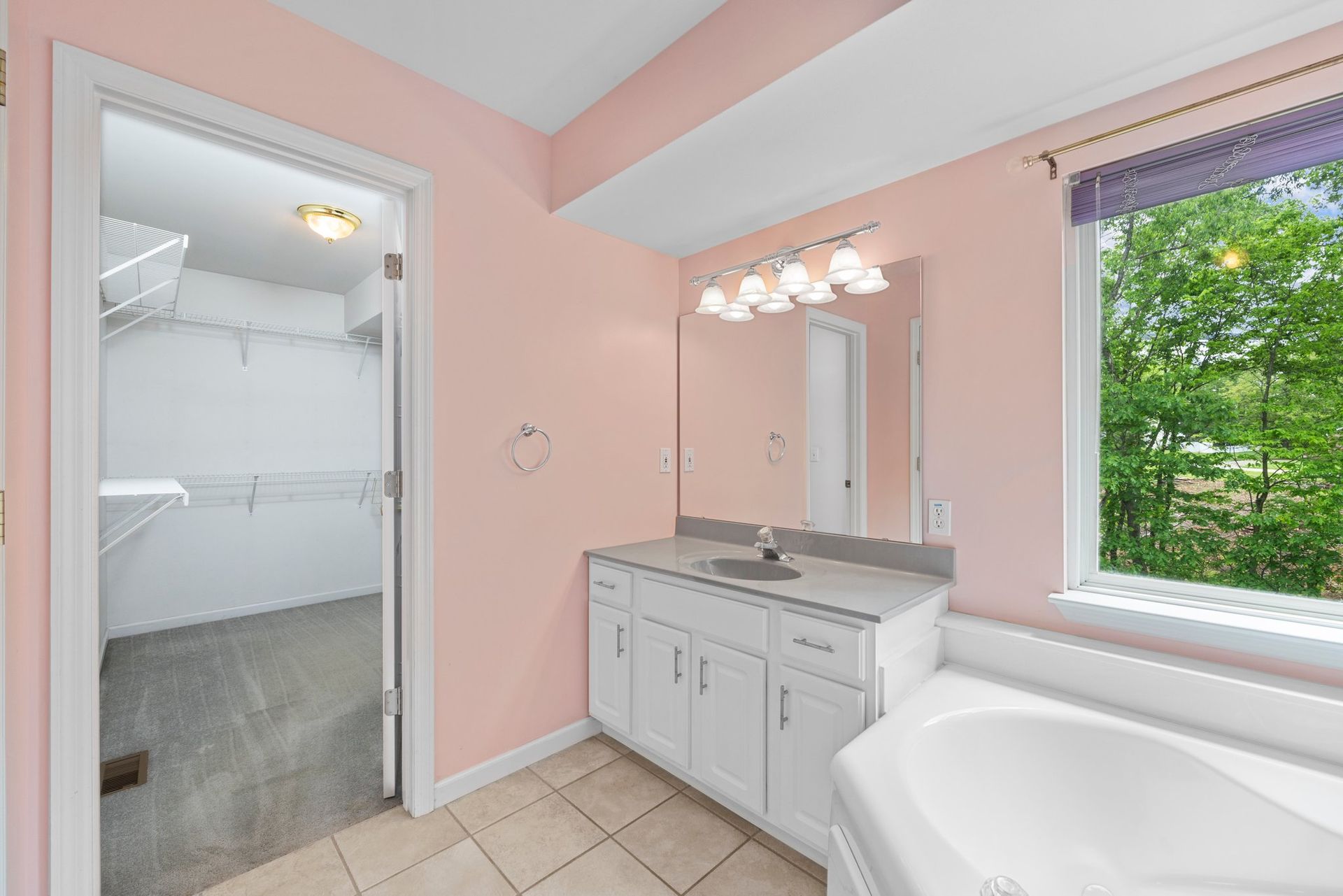 A bathroom with a tub , sink , mirror and walk in closet.