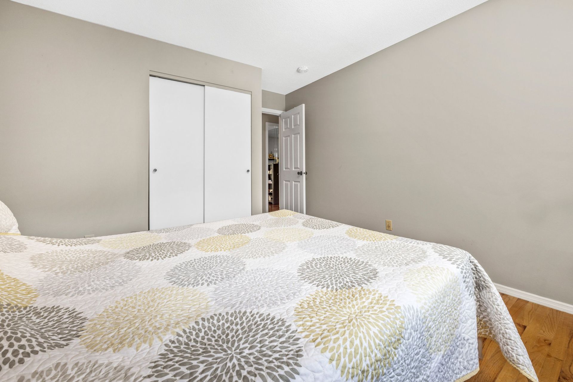 A bedroom with a bed , closet , and wooden floor.