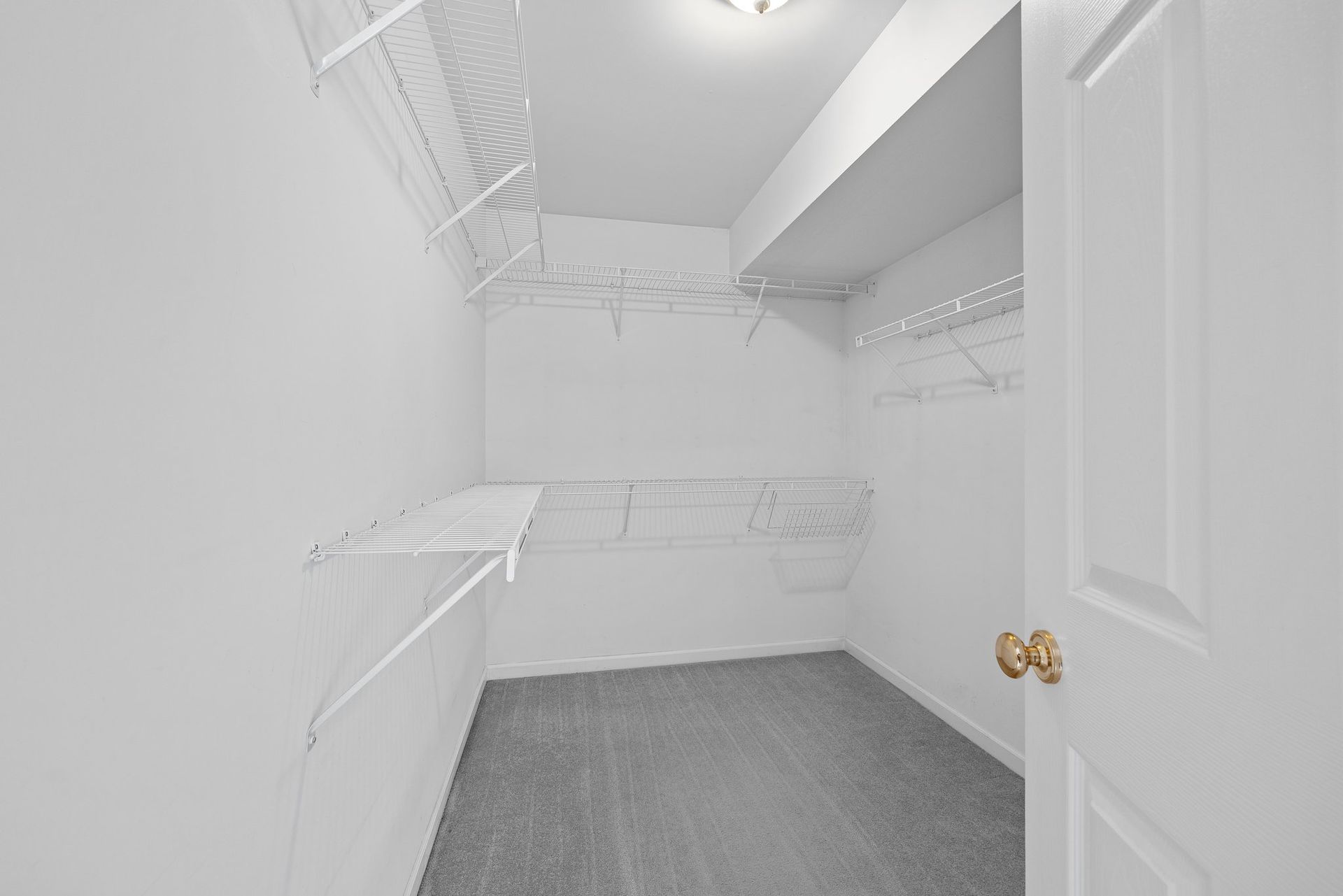 An empty walk in closet with a door and shelves.