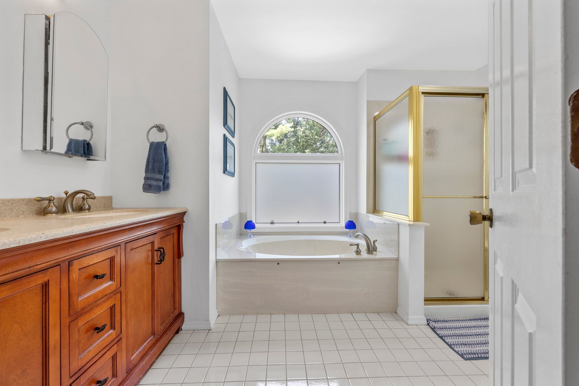 A bathroom with two sinks , a tub , a shower and a window.