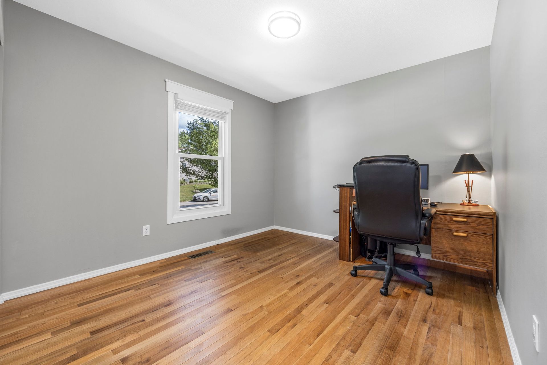 A bedroom with hardwood floors and a desk and chair.