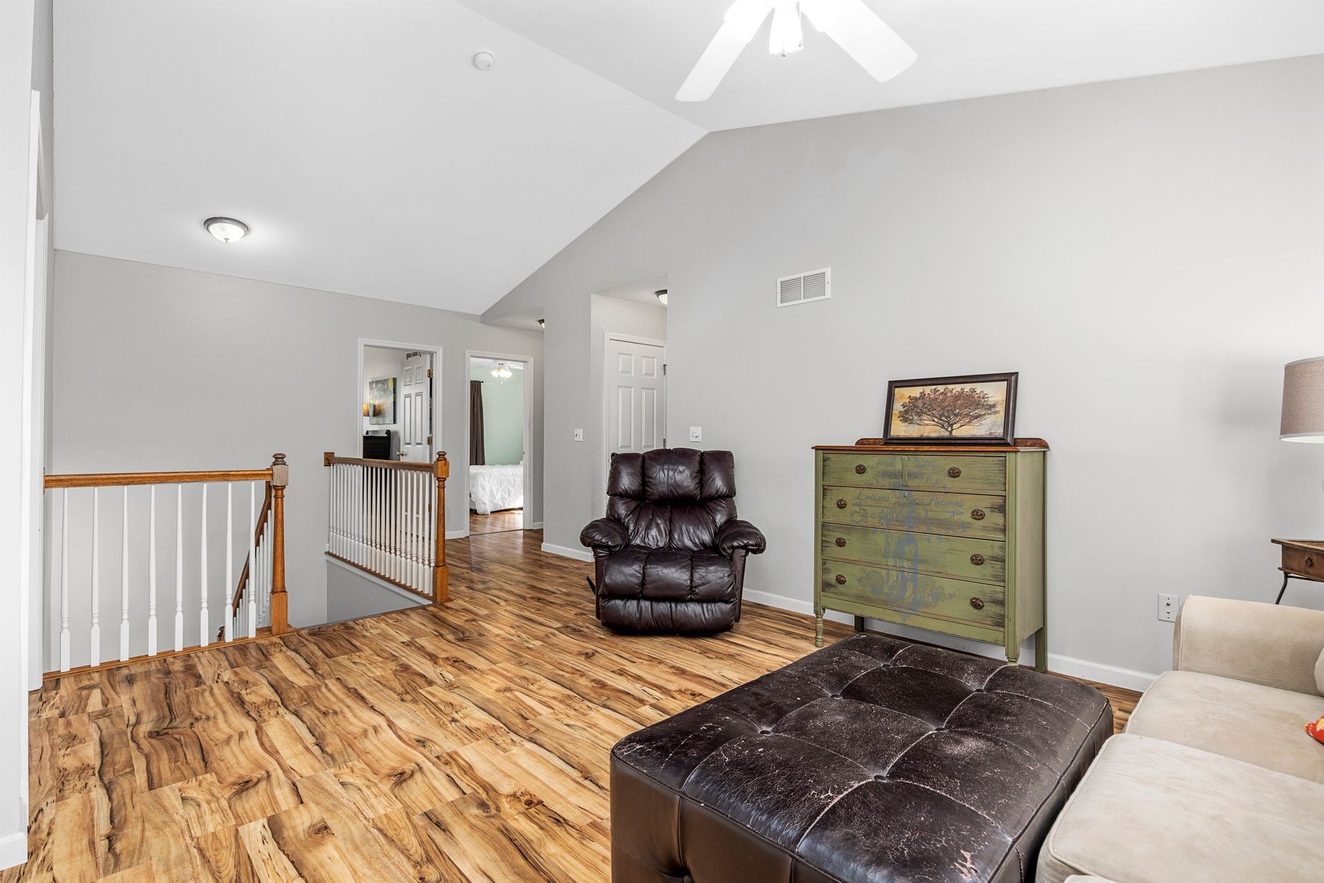 A living room with hardwood floors , a couch , chair and ottoman.