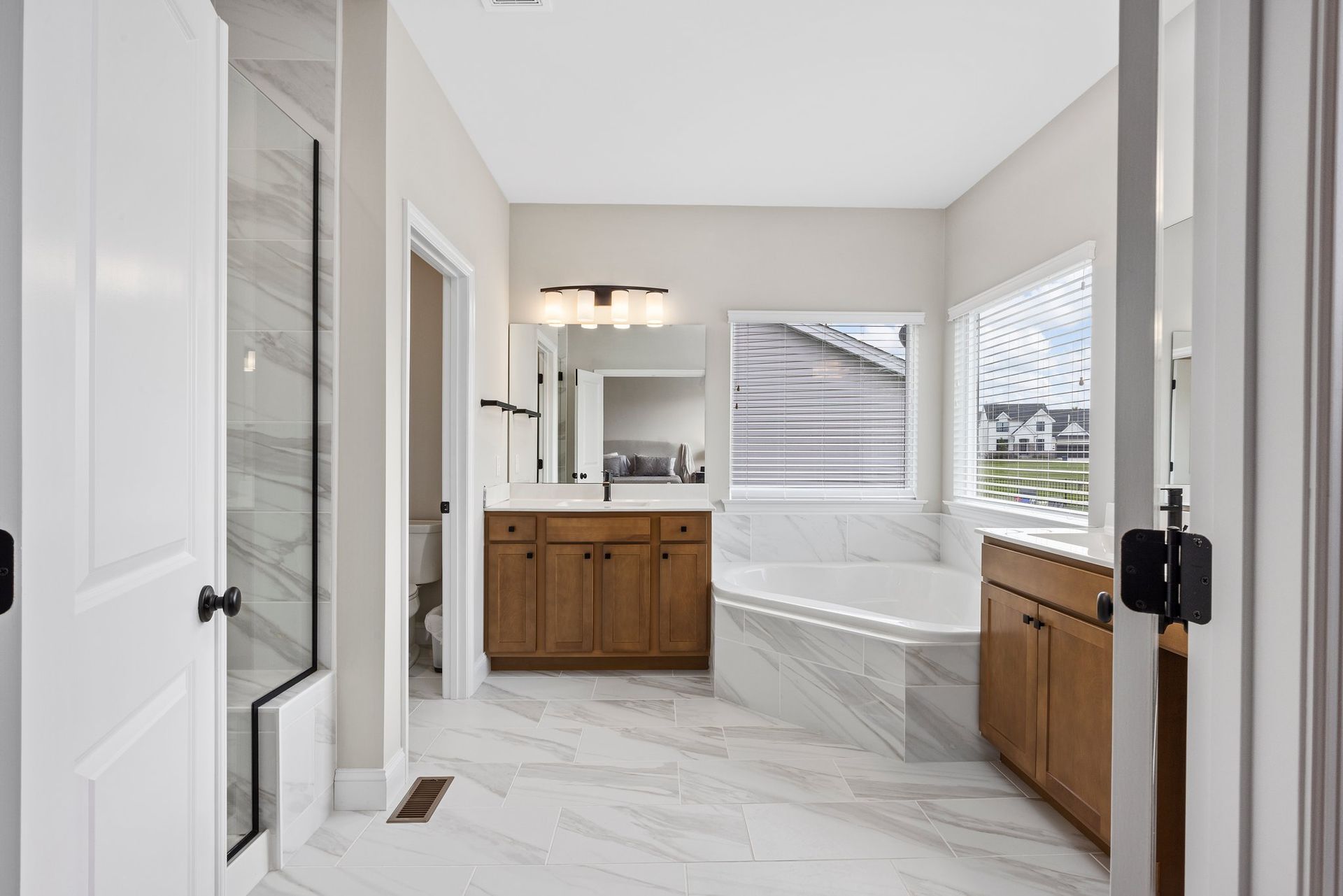 A bathroom with a tub , sink , mirror and window.