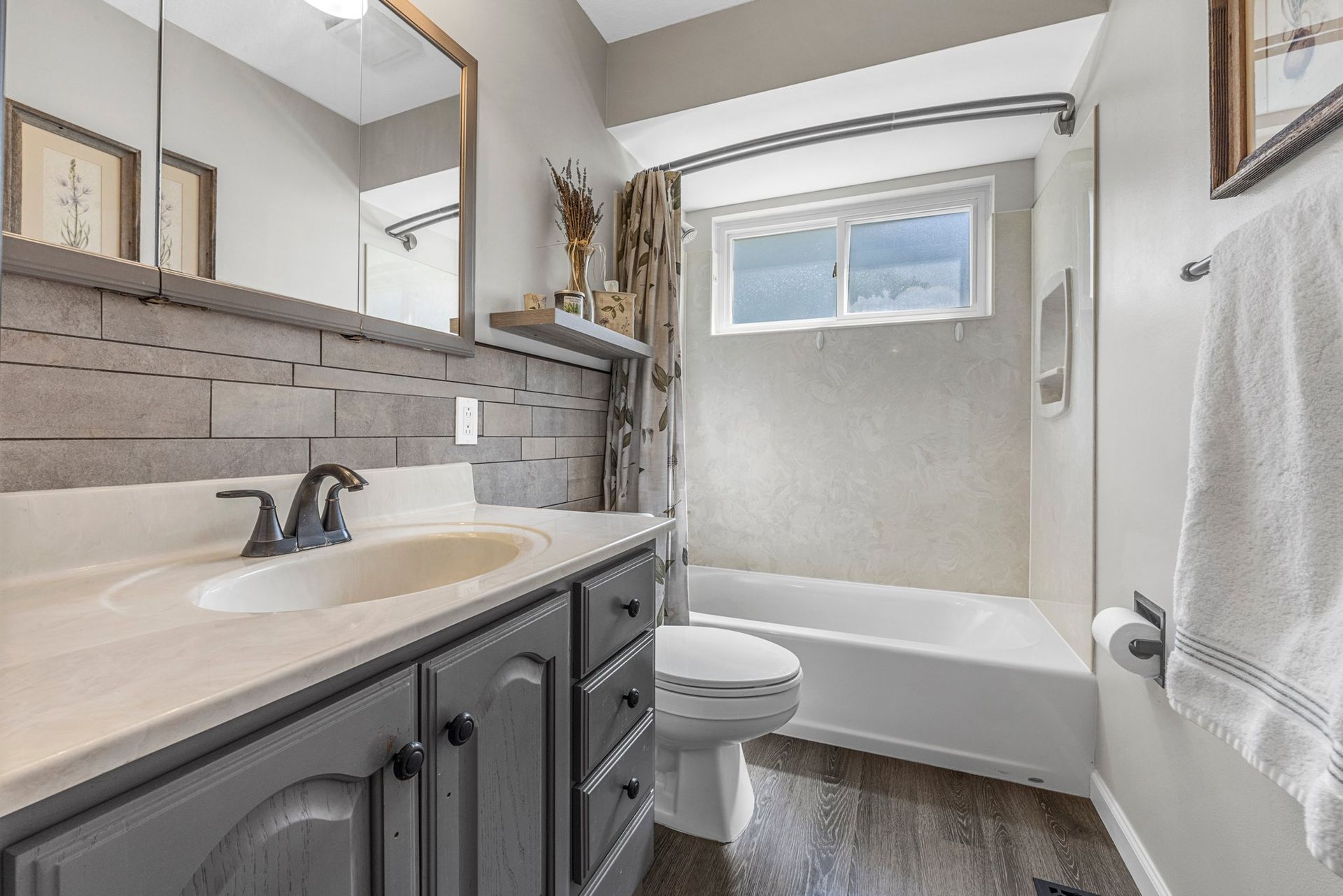A bathroom with a sink , toilet , bathtub and mirror.