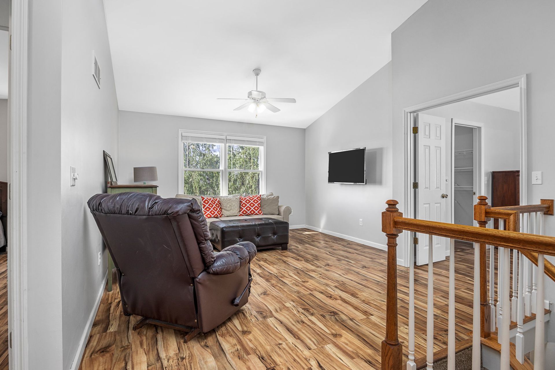 A living room with hardwood floors , a couch and a chair.