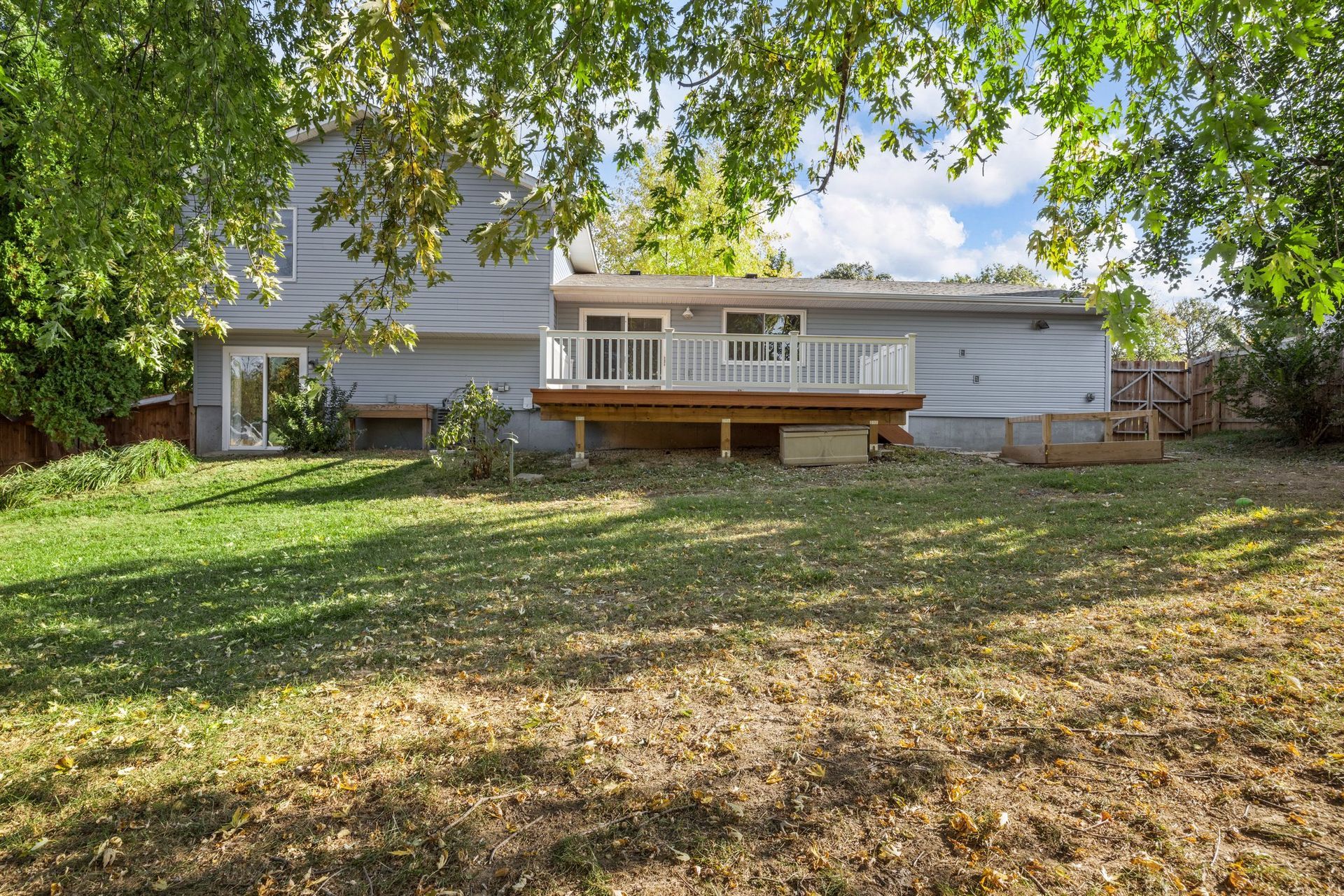 The backyard of a house with a large deck and a large lawn.