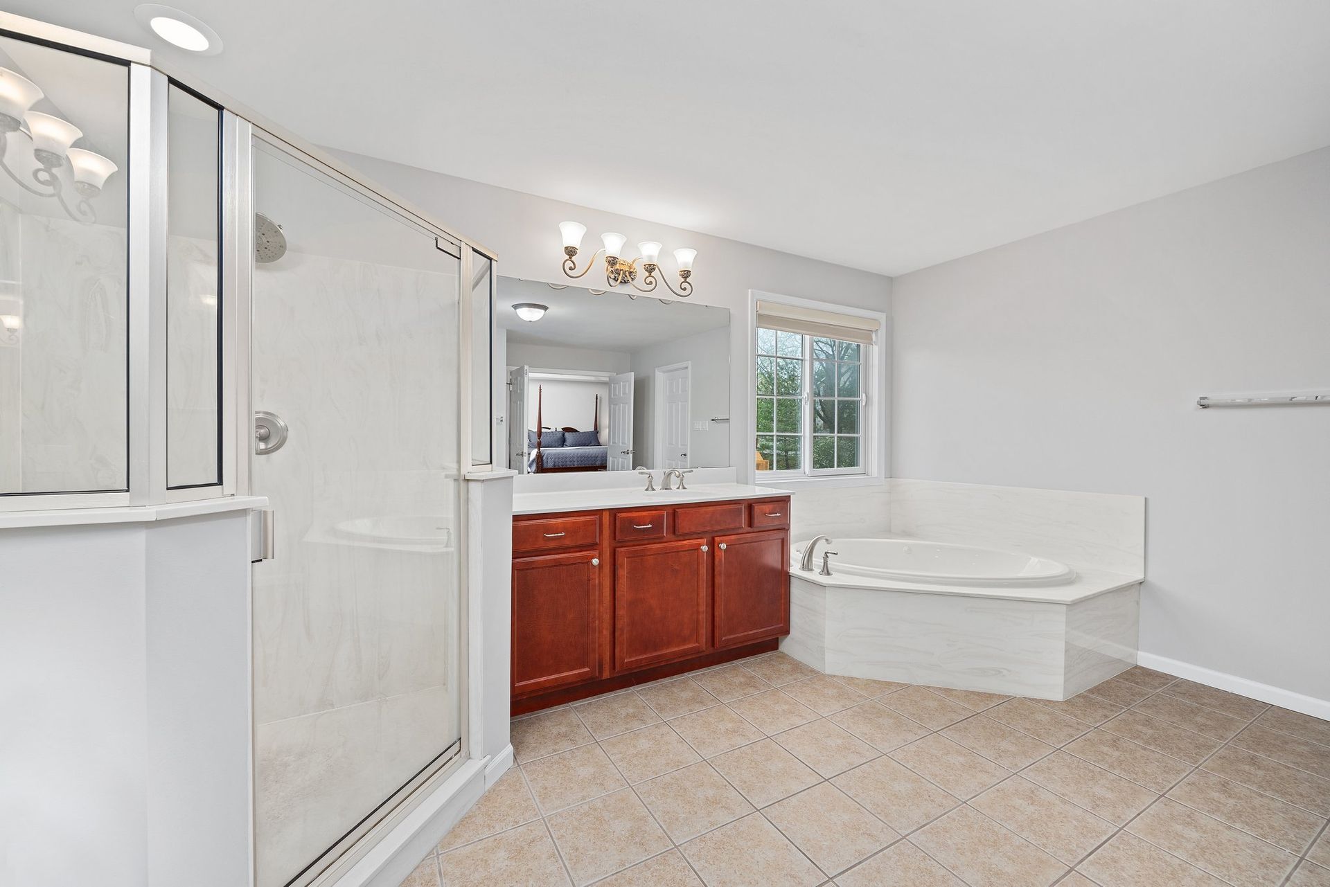 A bathroom with a tub , sink , shower and mirror.