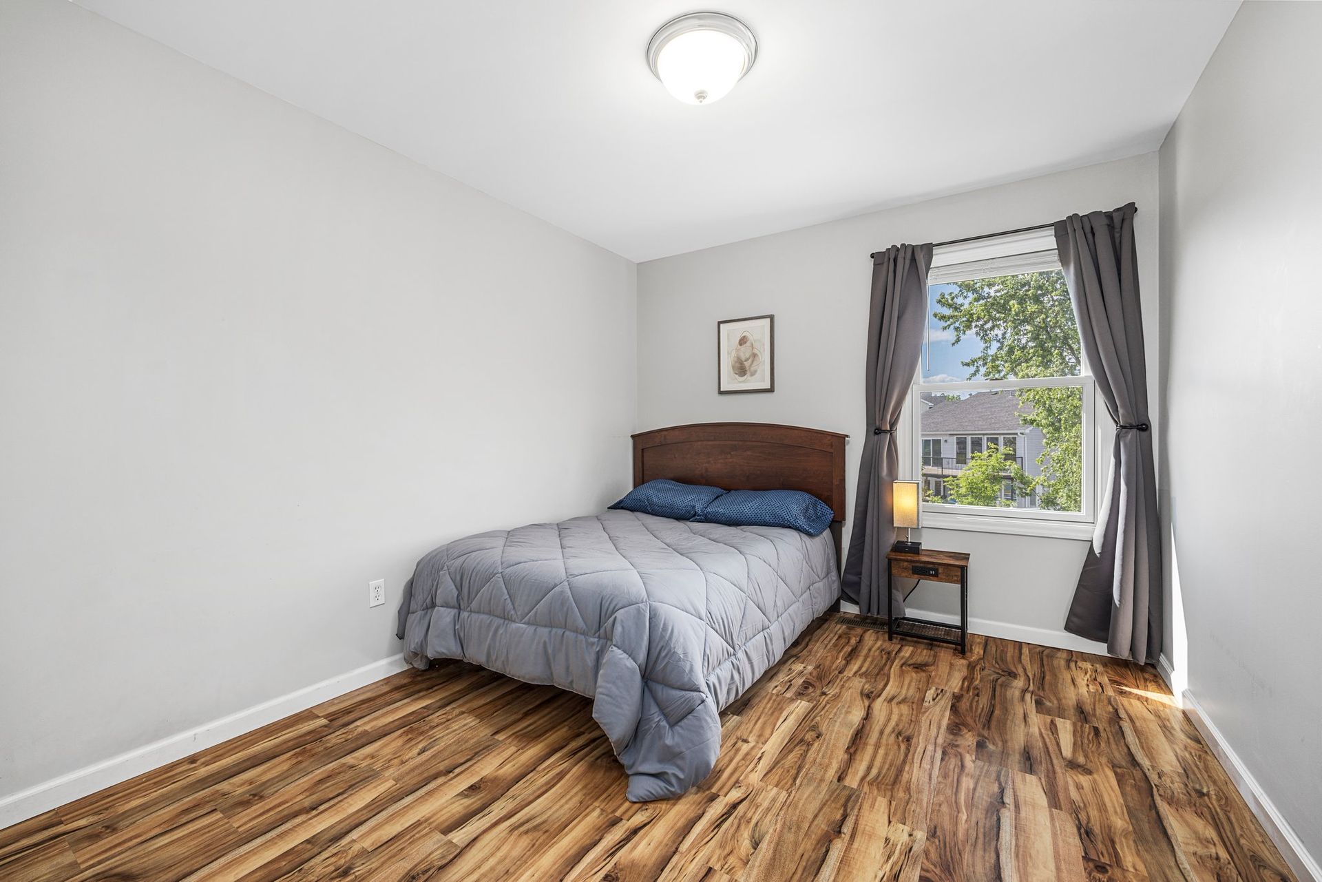 A bedroom with a bed , window and wooden floor.