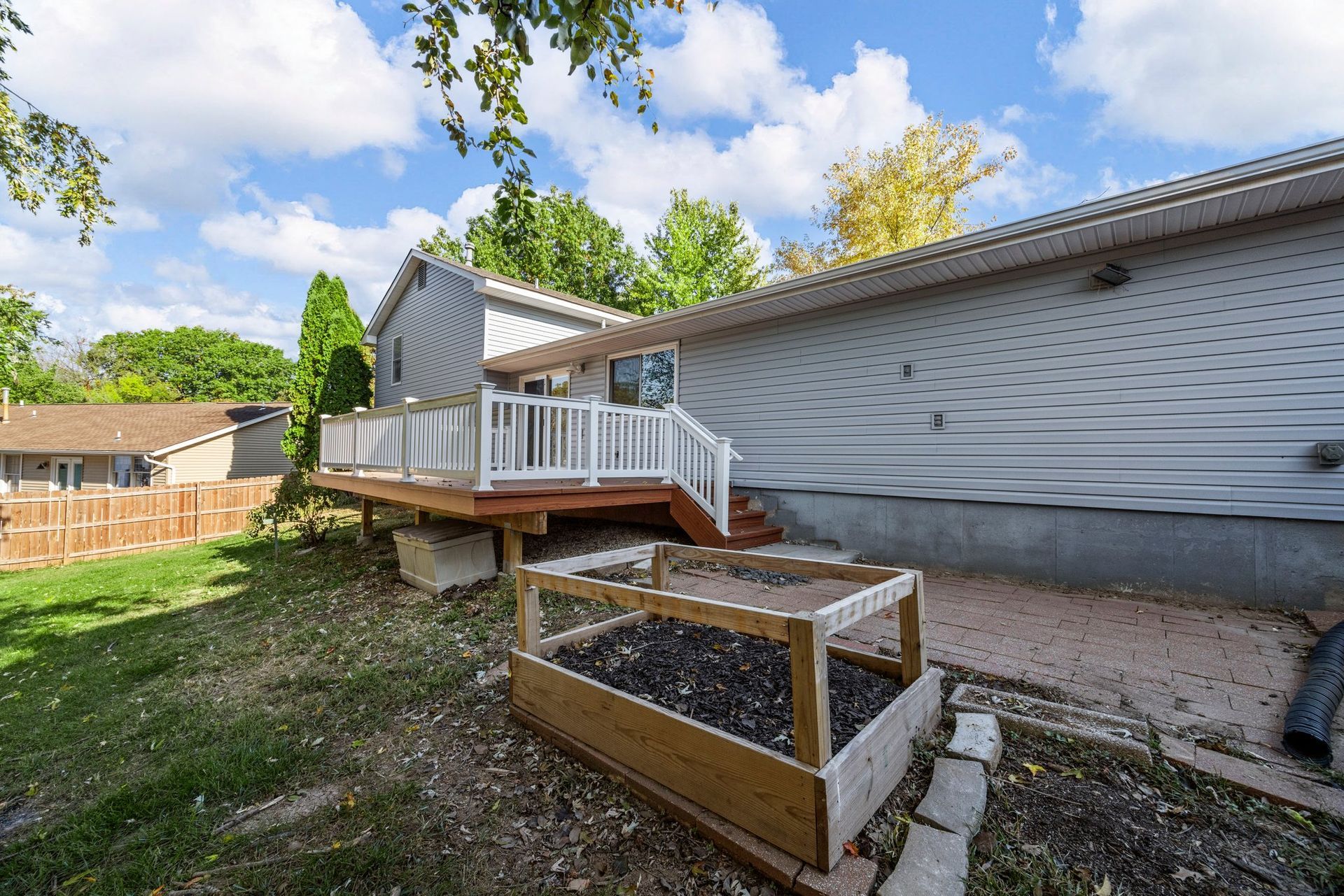 A house with a deck and a garden in front of it.