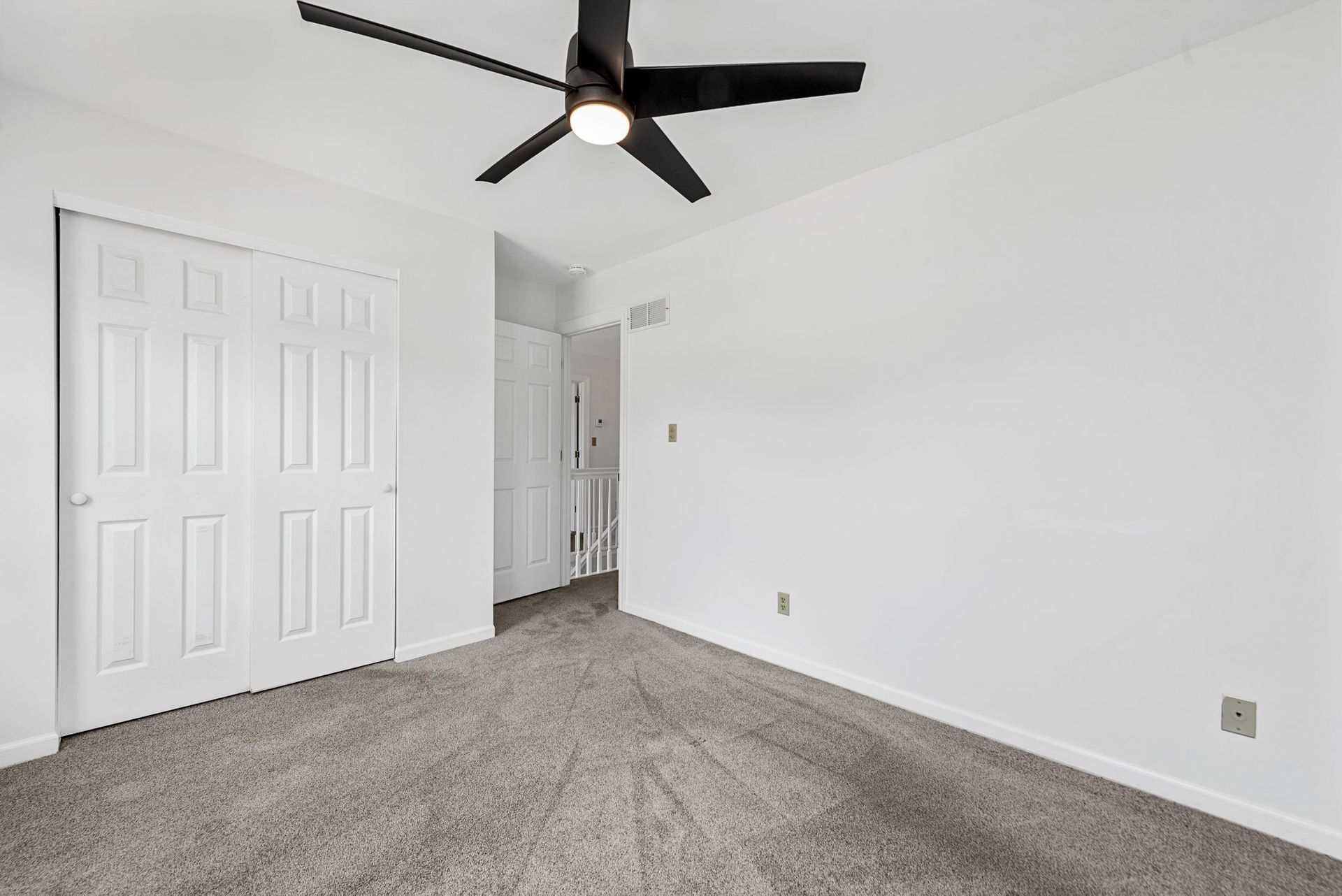 An empty bedroom with a ceiling fan and a closet.
