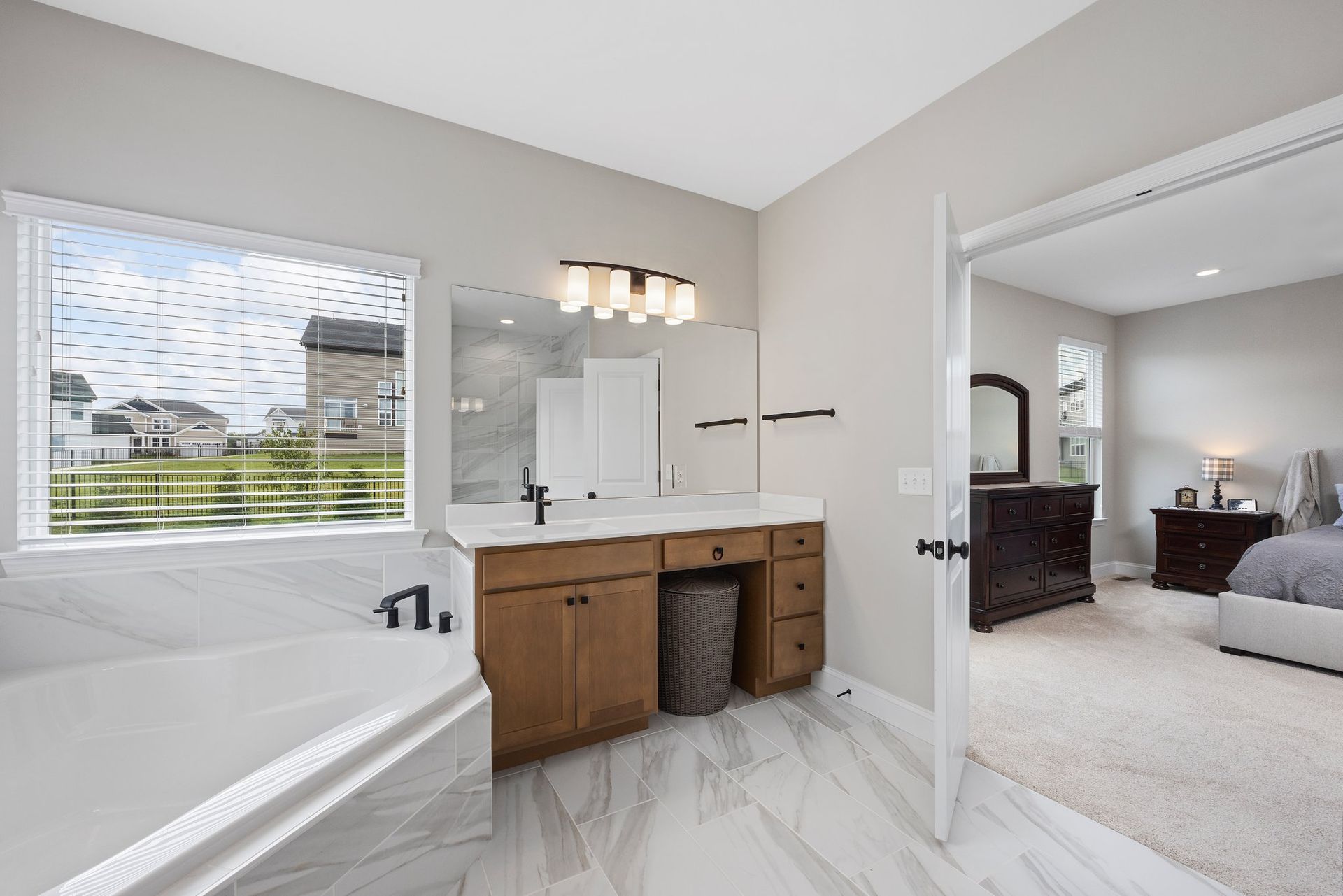 A bathroom with a tub , sink , mirror and window.