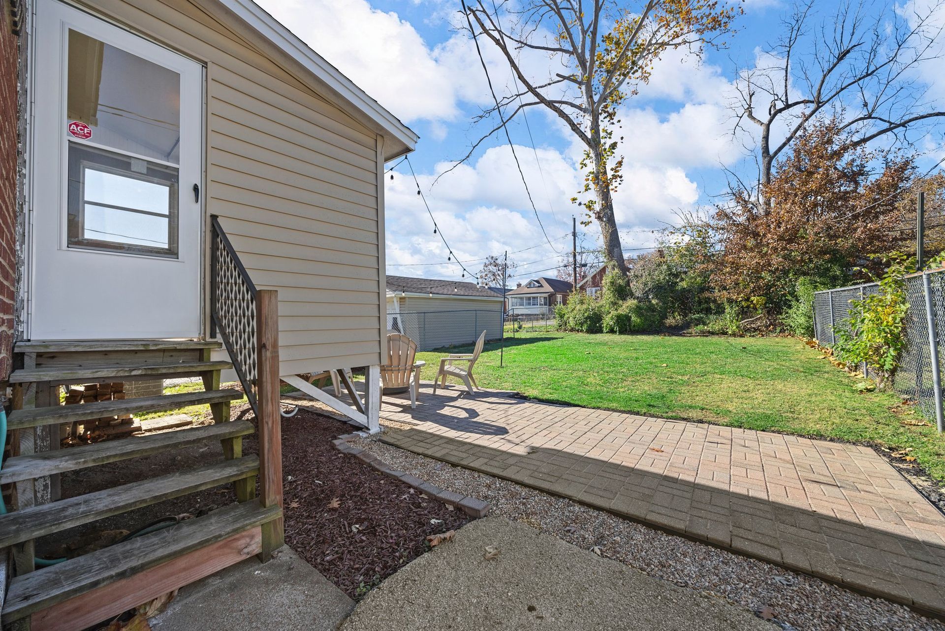A small house with stairs leading up to it and a patio in front of it.