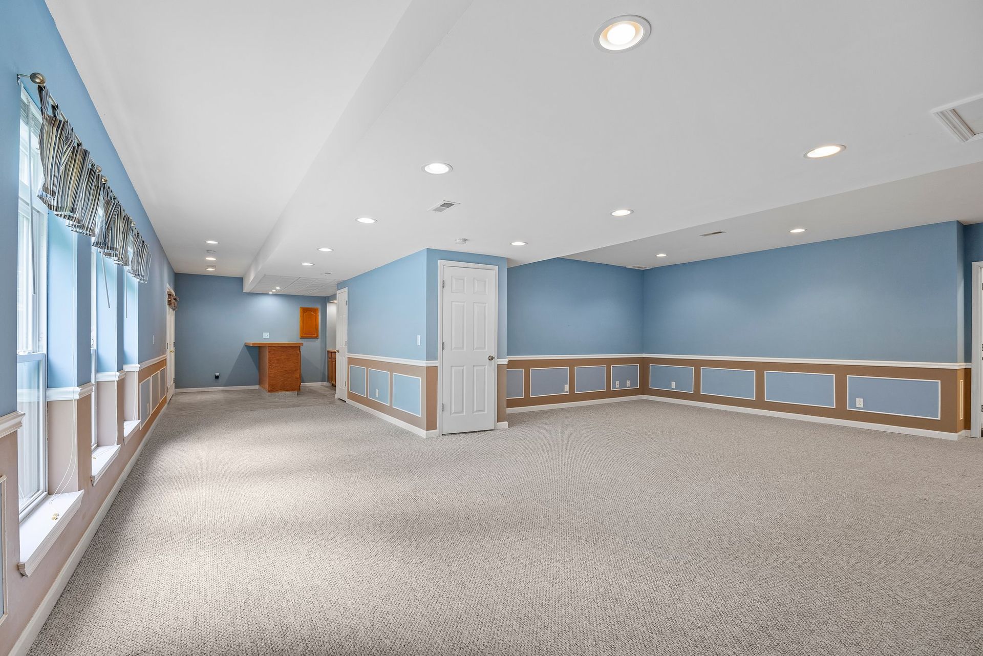 An empty basement with blue walls and a carpeted floor