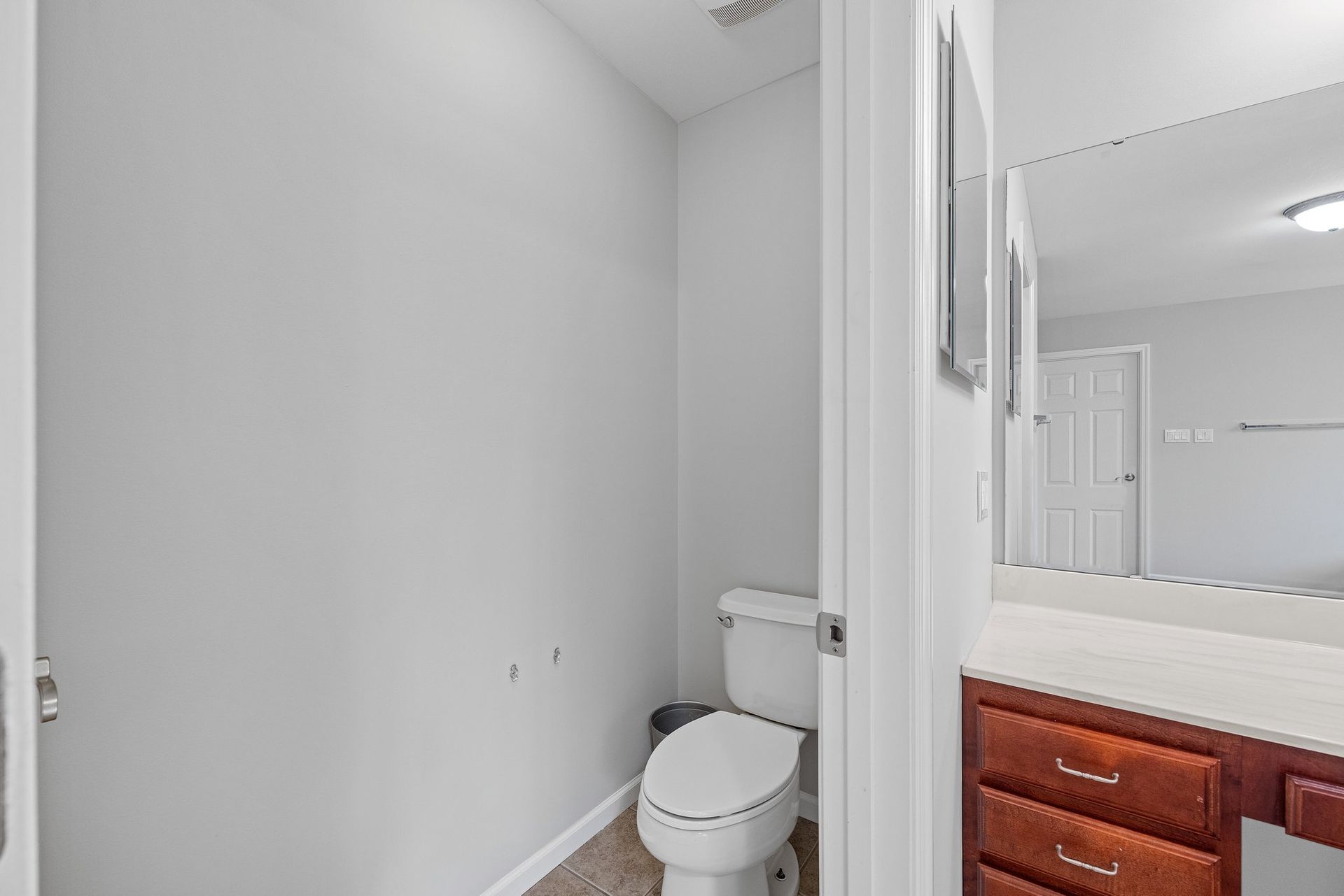 A bathroom with a toilet , sink and mirror.