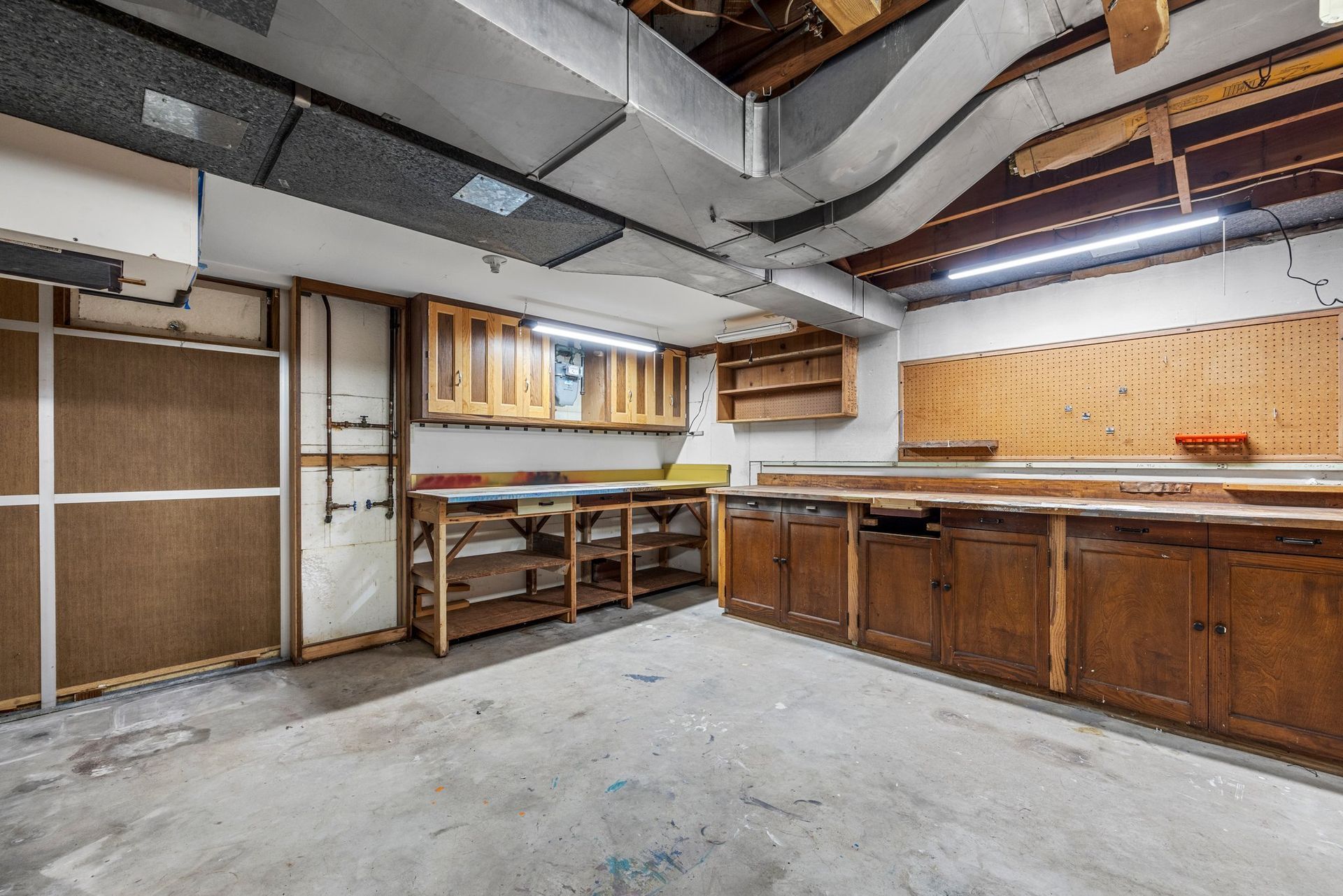 A large empty room with wooden cabinets and workbench.