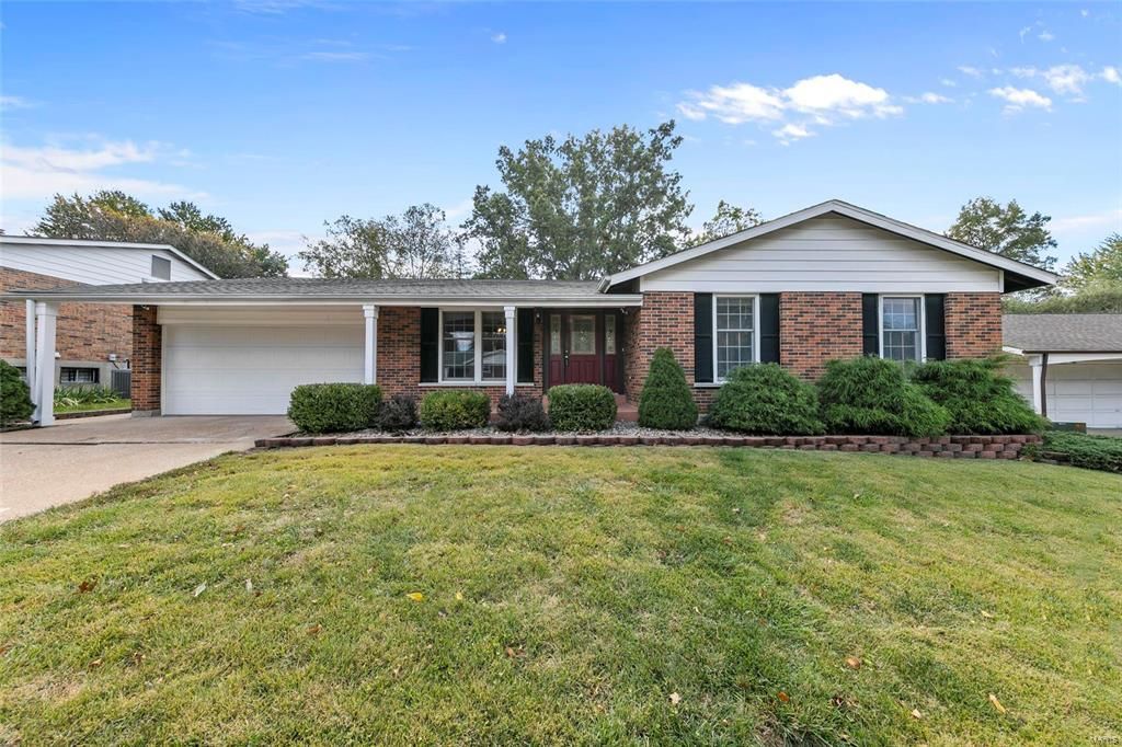 A brick house with a large lawn in front of it.