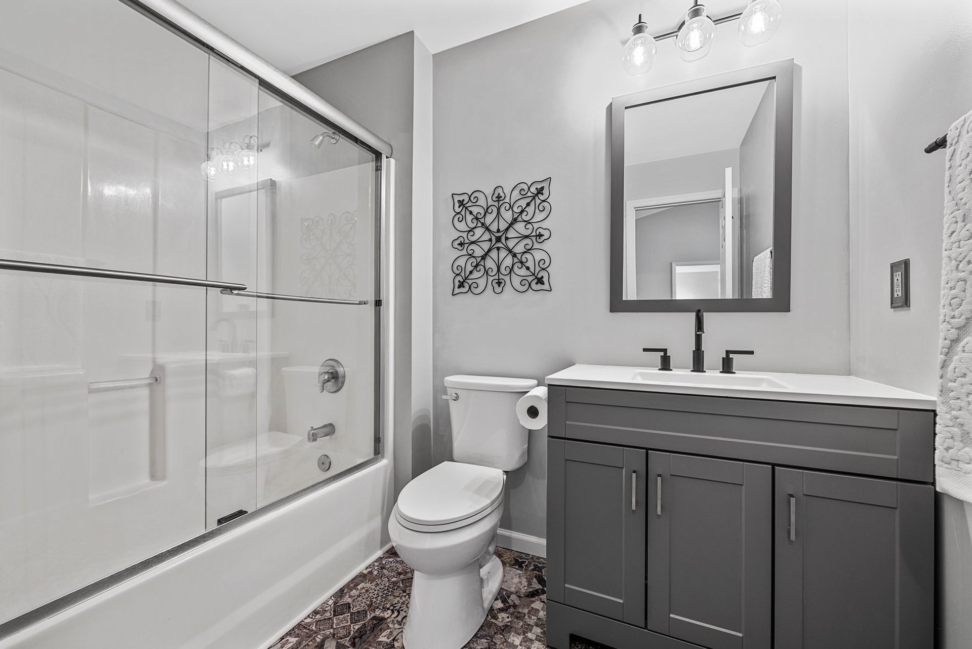 A bathroom with a toilet , sink , shower and mirror.