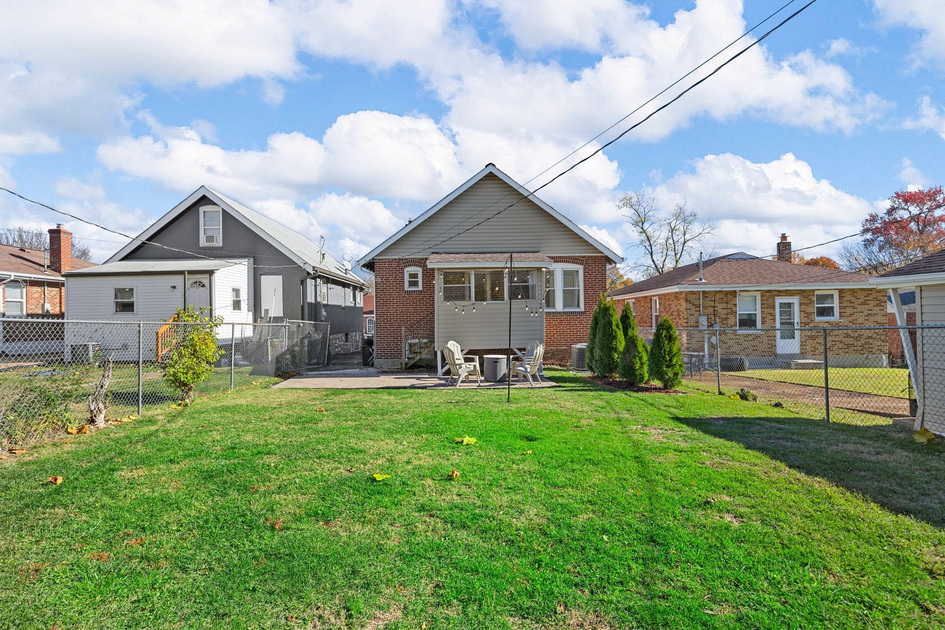 The backyard of a house with a large lawn and a picnic table.