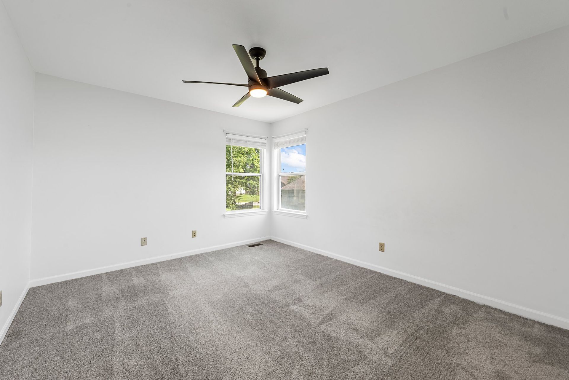 An empty bedroom with a ceiling fan and a window.