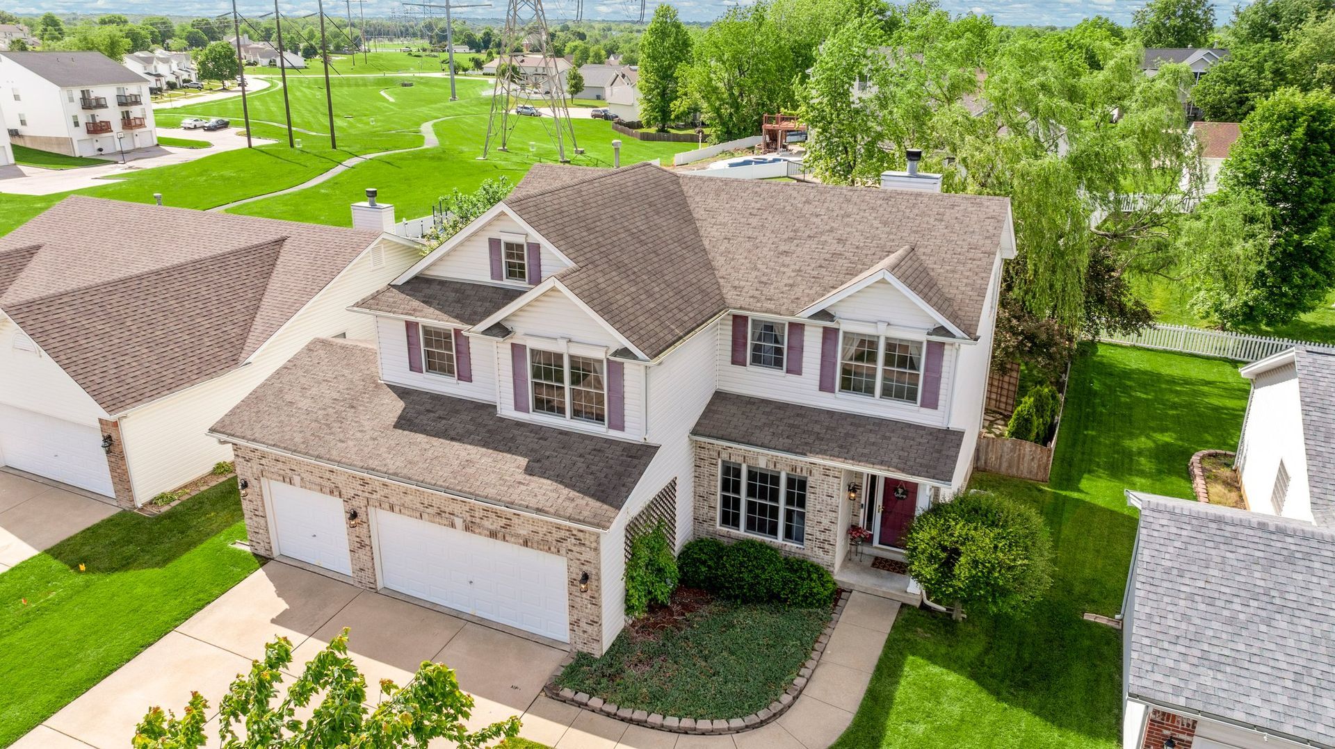 An aerial view of a large white house with a brown roof in a residential area.