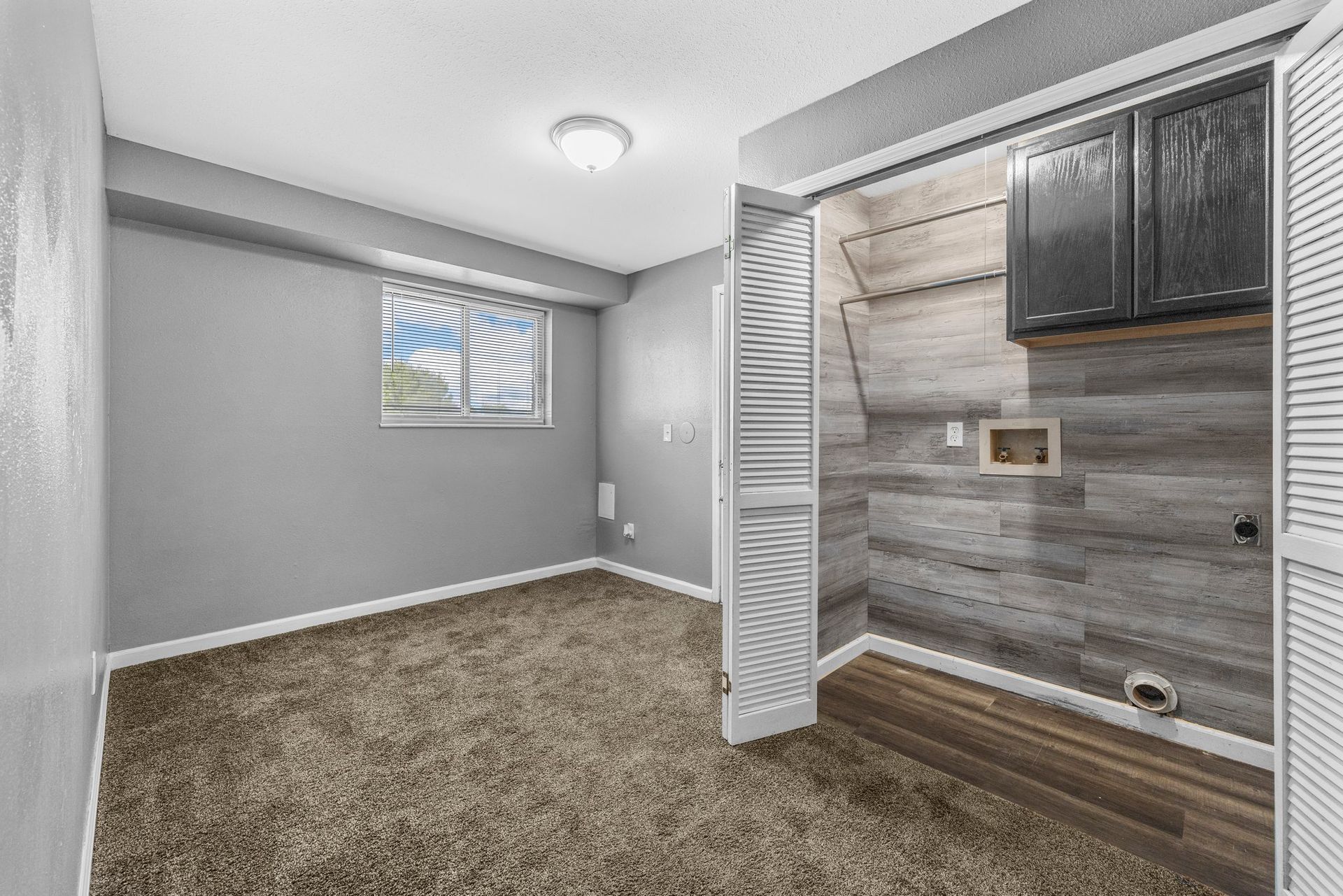 An empty room with a carpeted floor and a window.