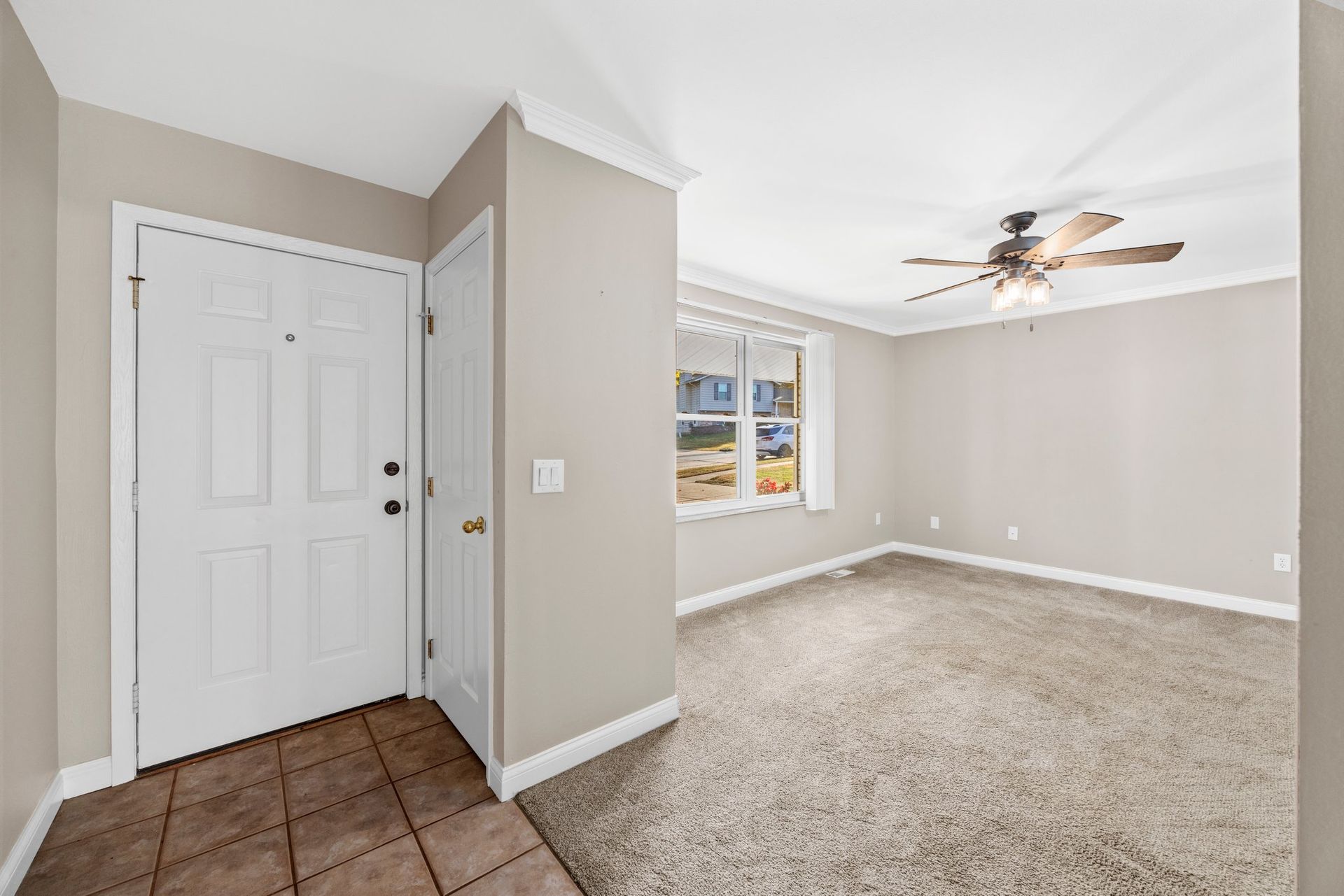 A living room with a ceiling fan and a door.