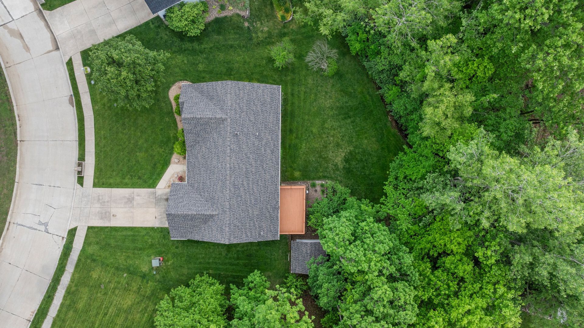 An aerial view of a house surrounded by trees and grass.