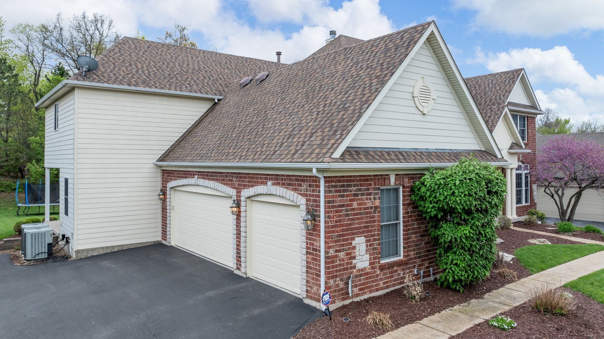 A large house with two garage doors and a brick roof.