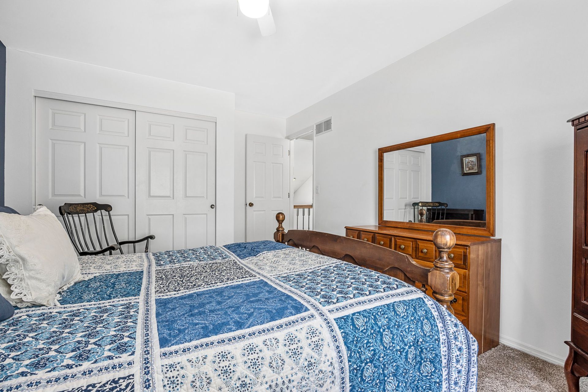 A bedroom with a bed , dresser , mirror and chair.