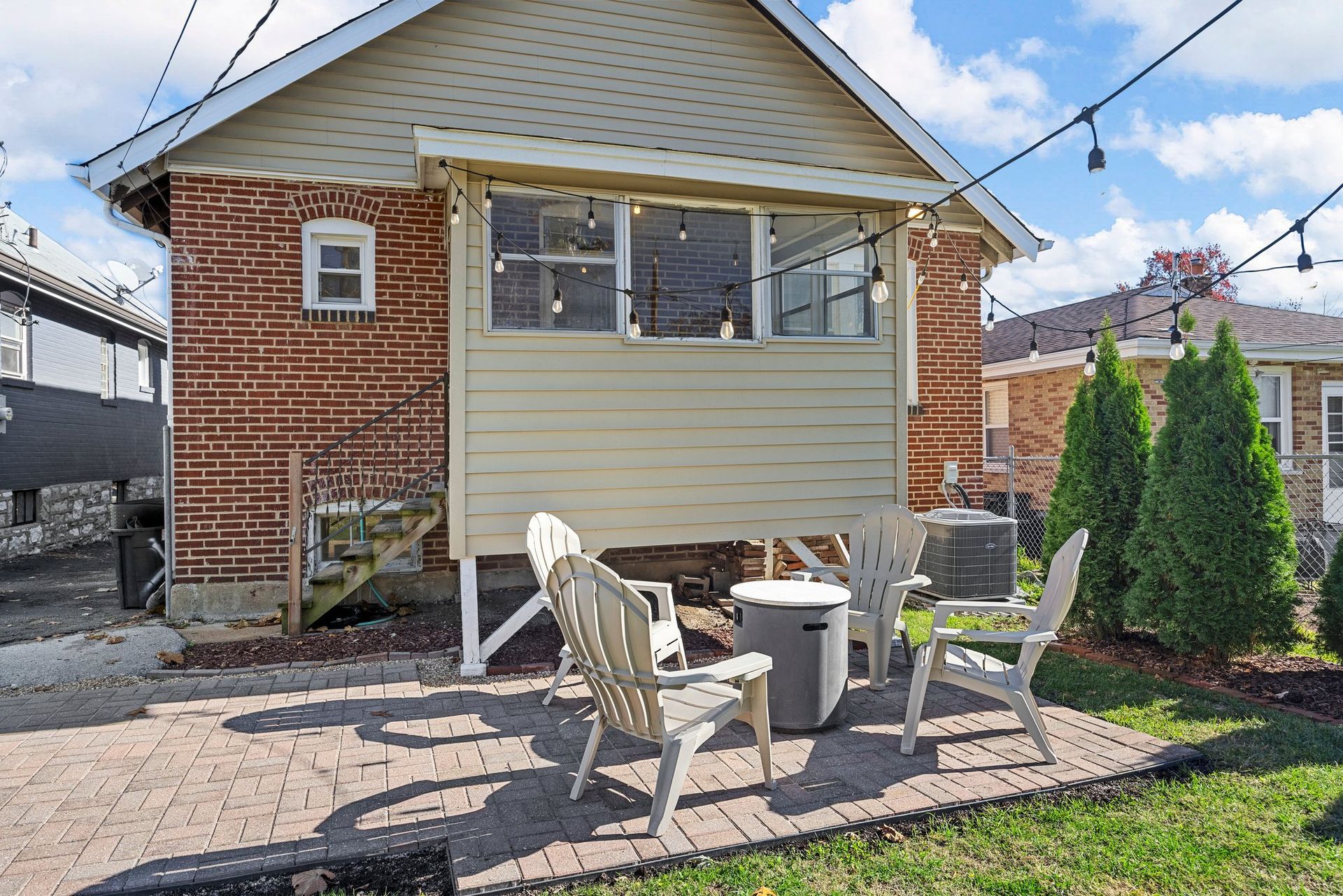 A brick house with a patio and chairs in front of it.