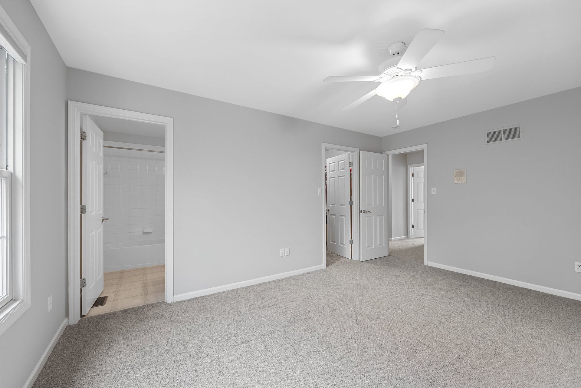 An empty bedroom with a ceiling fan and a walk in closet.