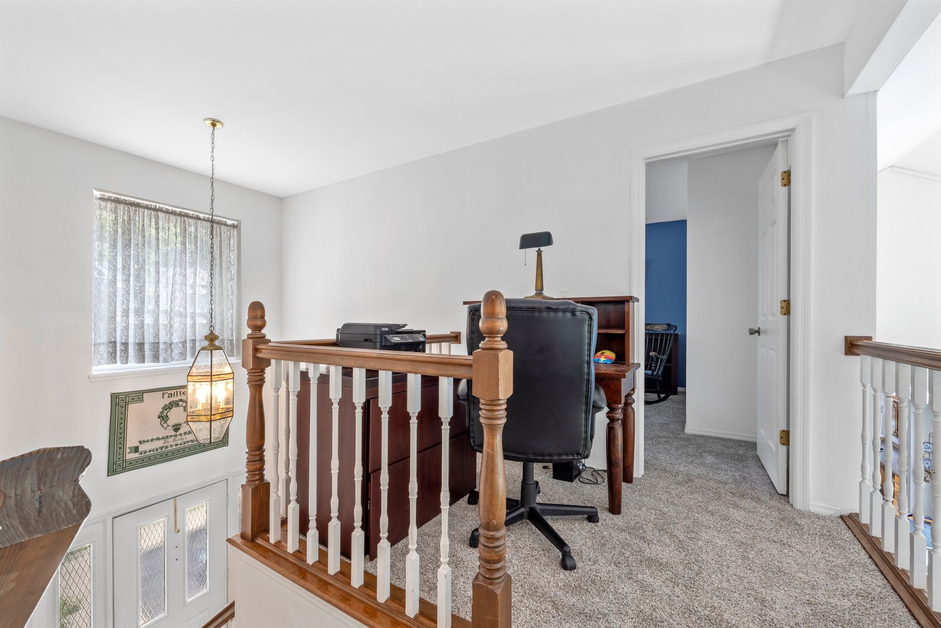 A home office with a desk and chair on the second floor of a house.