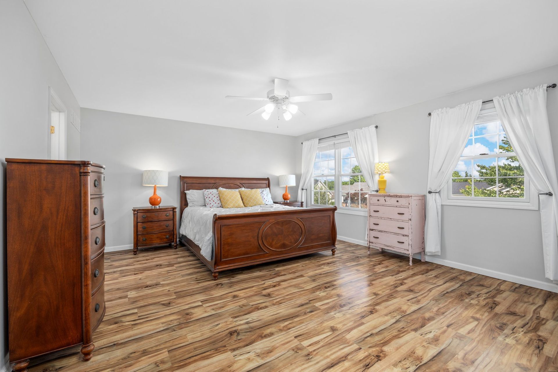 A bedroom with a king size bed , dresser , nightstand , and window.