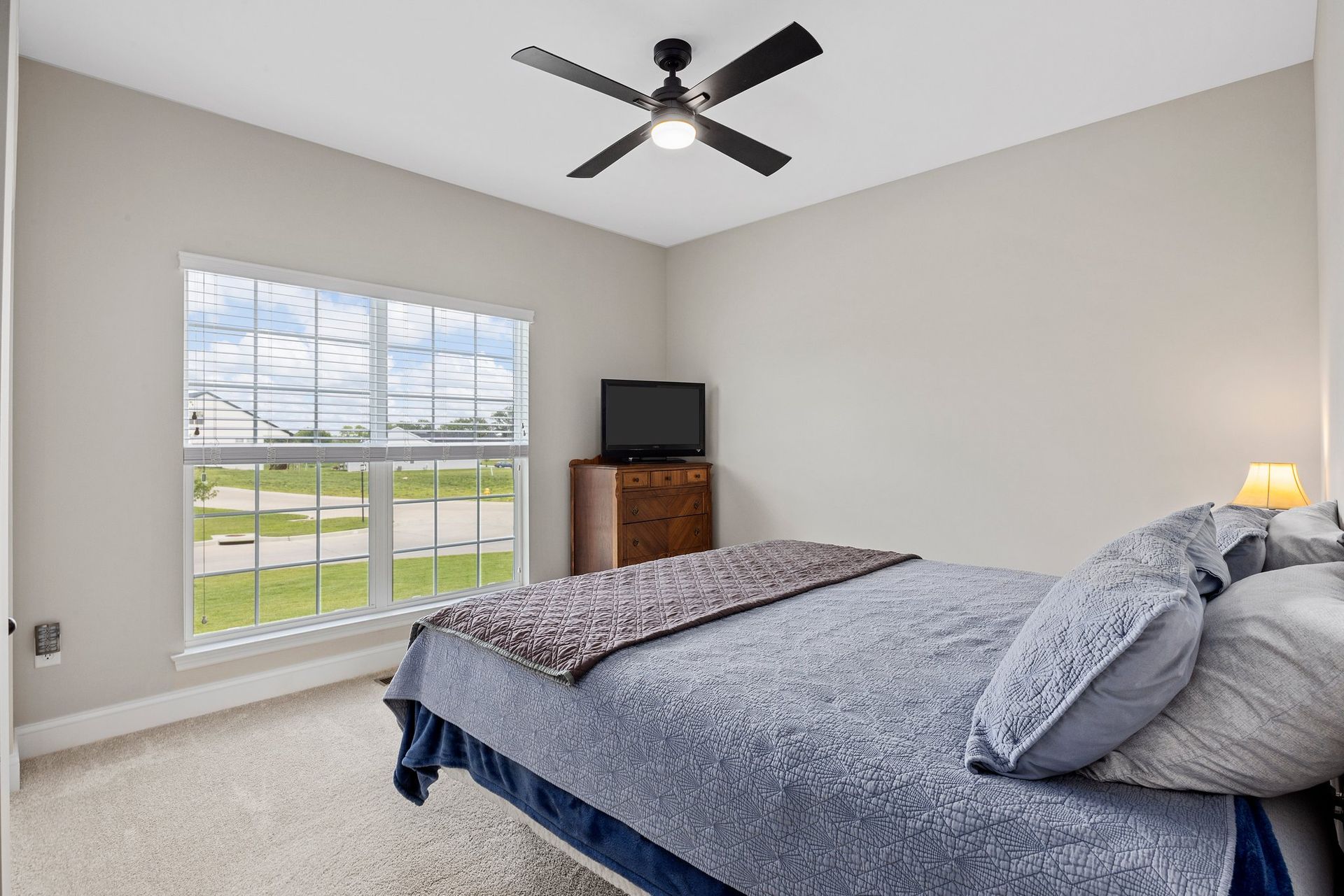 A bedroom with a bed , ceiling fan , television and window.