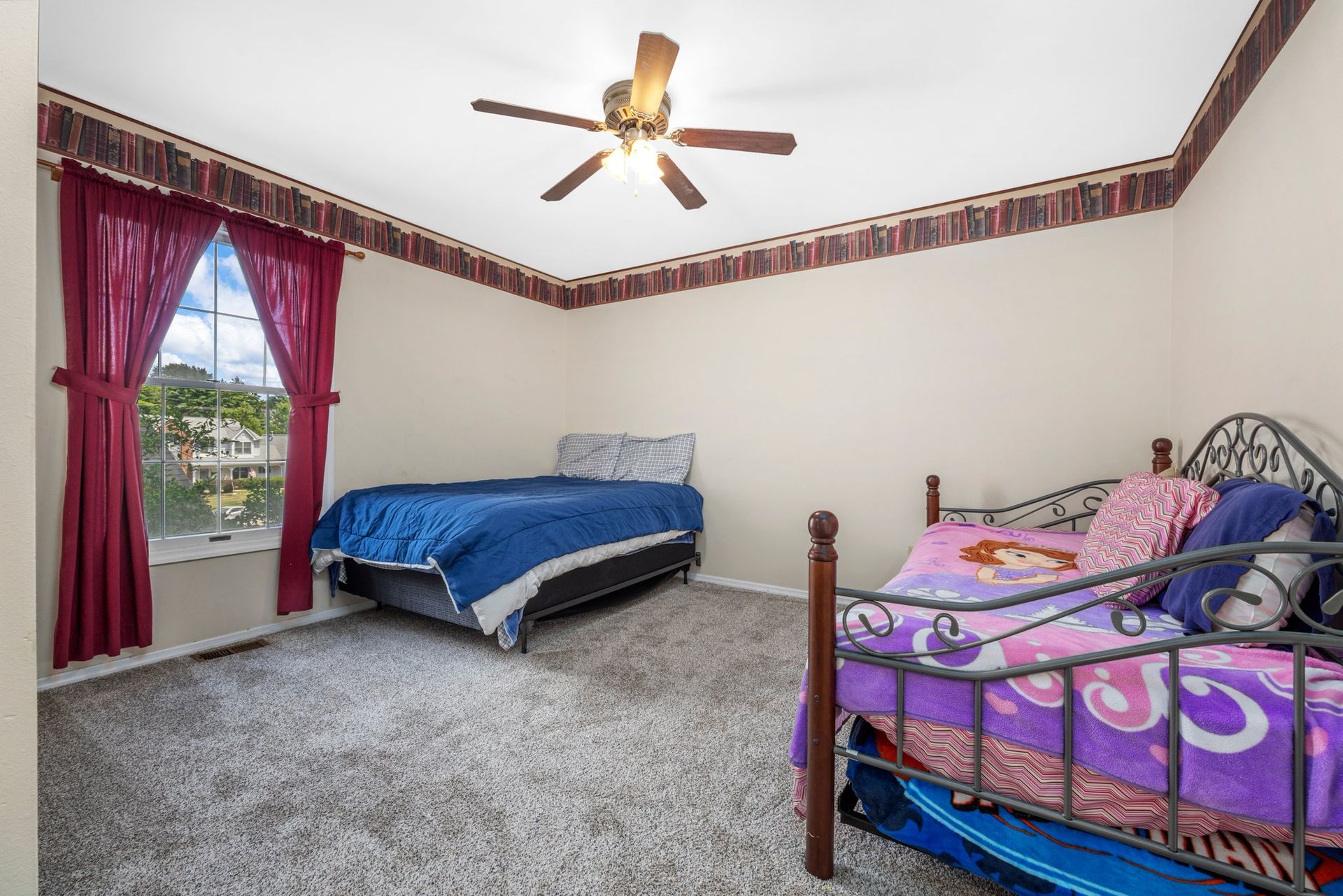 A bedroom with two beds and a ceiling fan.